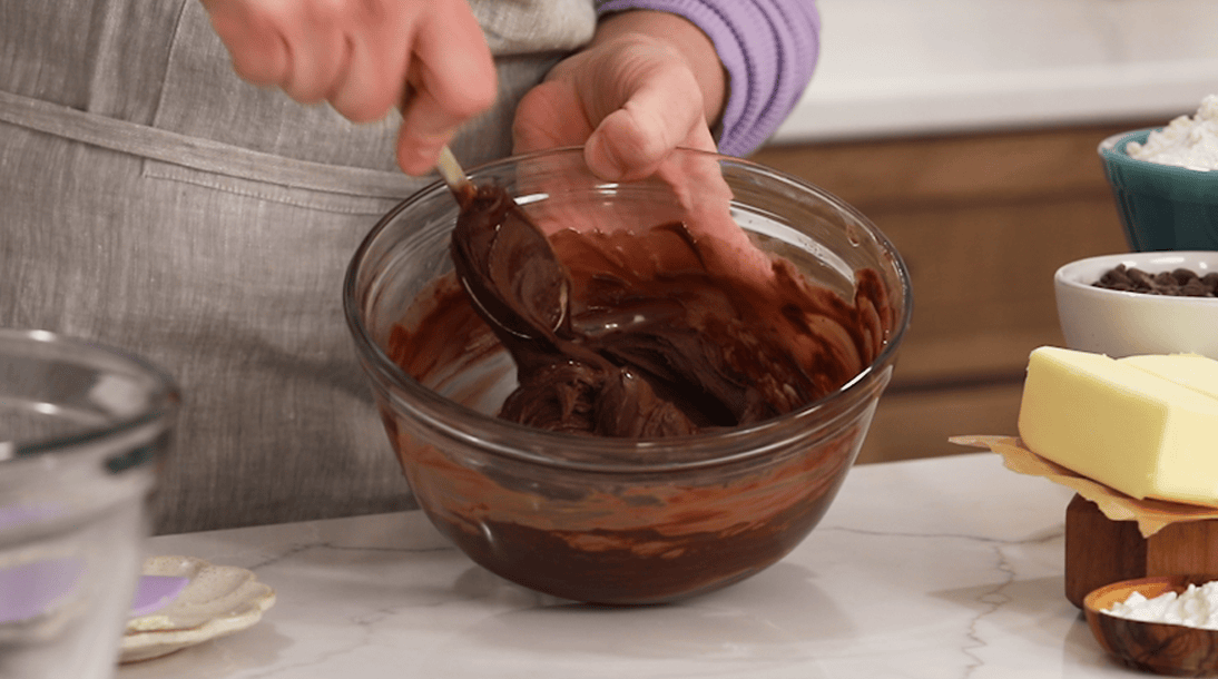 Bowl of melted butter and chocolate being stirred with a spoon.