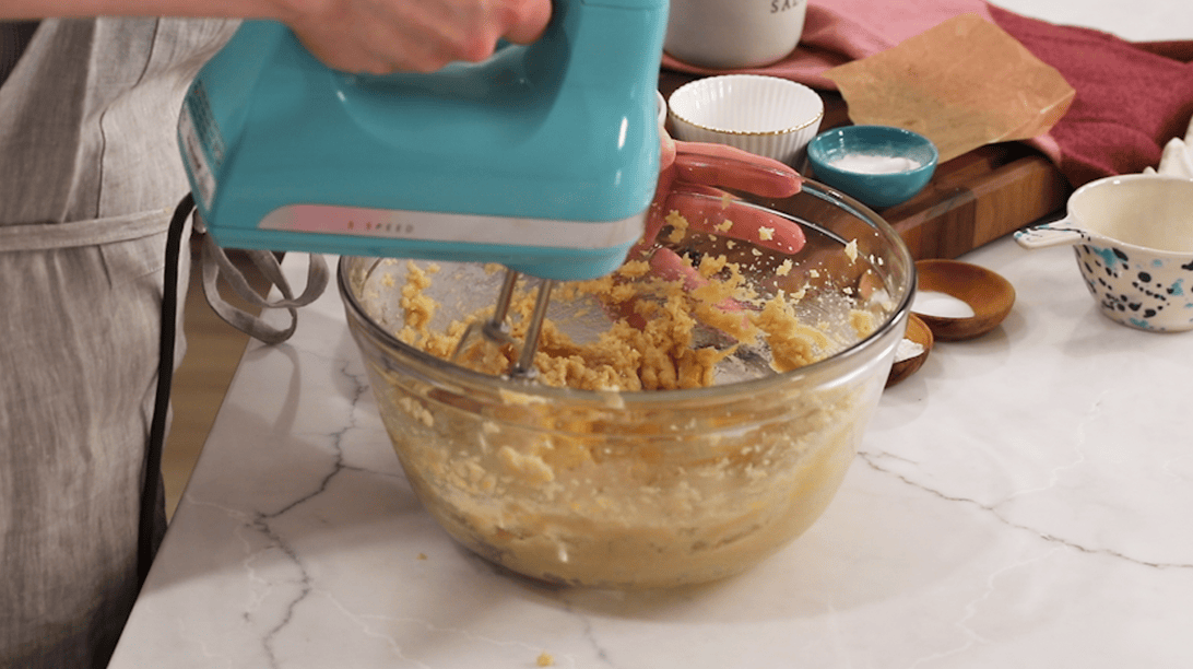 Eggs being mixed into creamed butter and sugars.