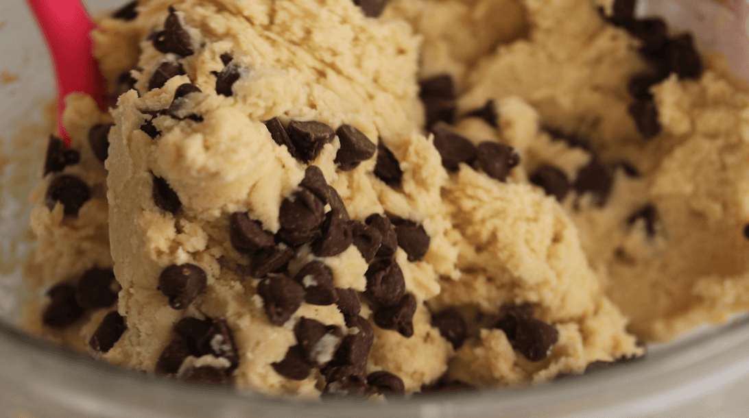 Chocolate chips being folded into a cookie dough.