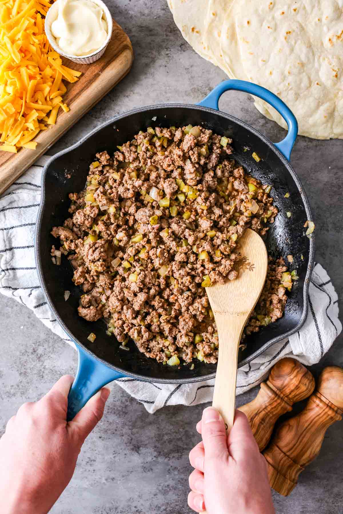 Skillet of ground beef seasoned with onions, pickles, ketchup, and more.