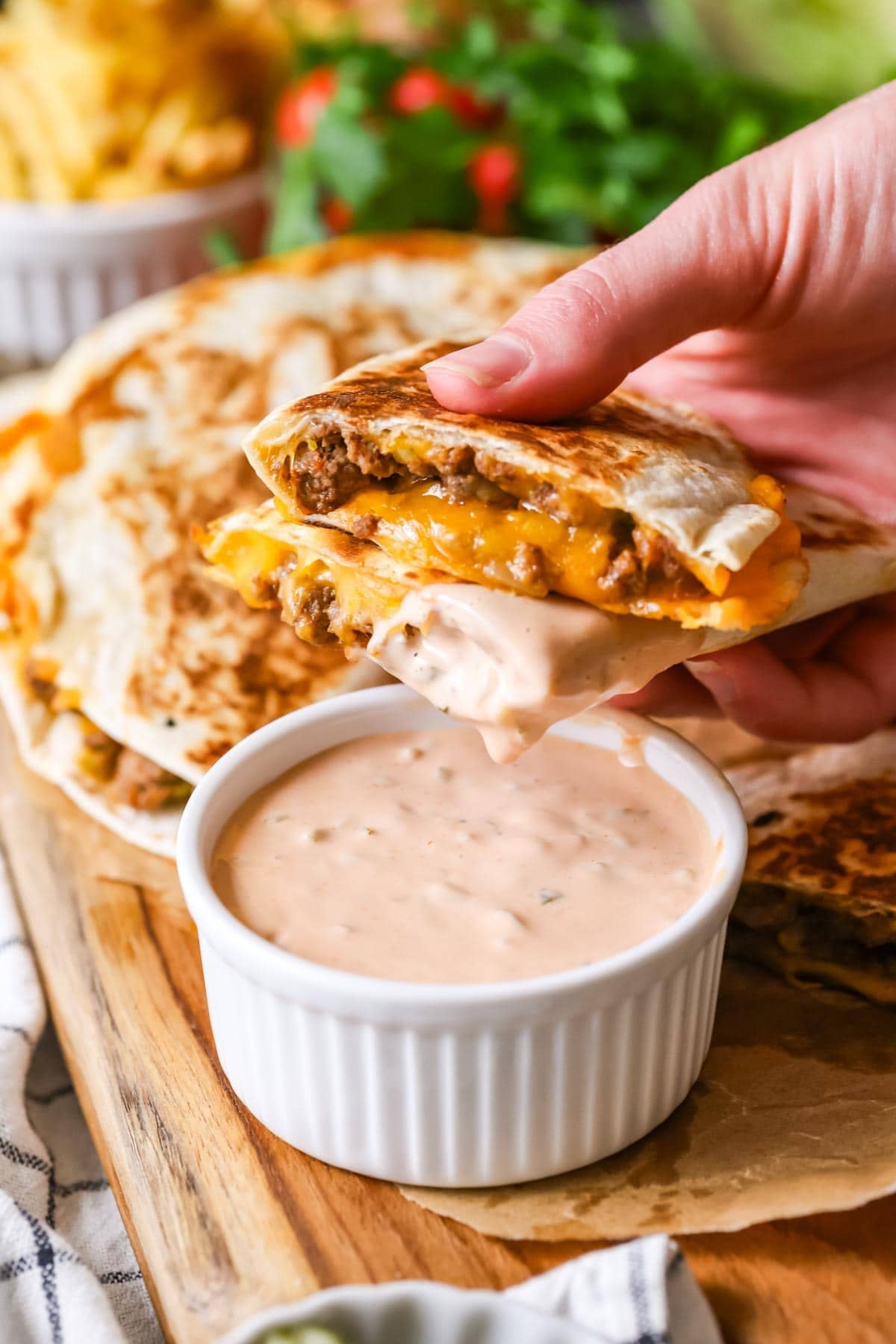 Beef and cheese quesadillas being dipped in burger sauce.