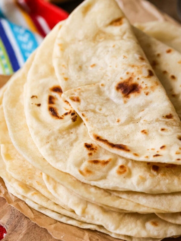 Pile of homemade flour tortillas with the top tortilla folded over.