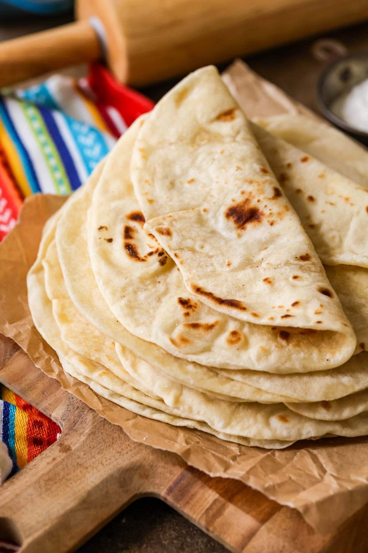 Pile of homemade flour tortillas with the top tortilla folded over.
