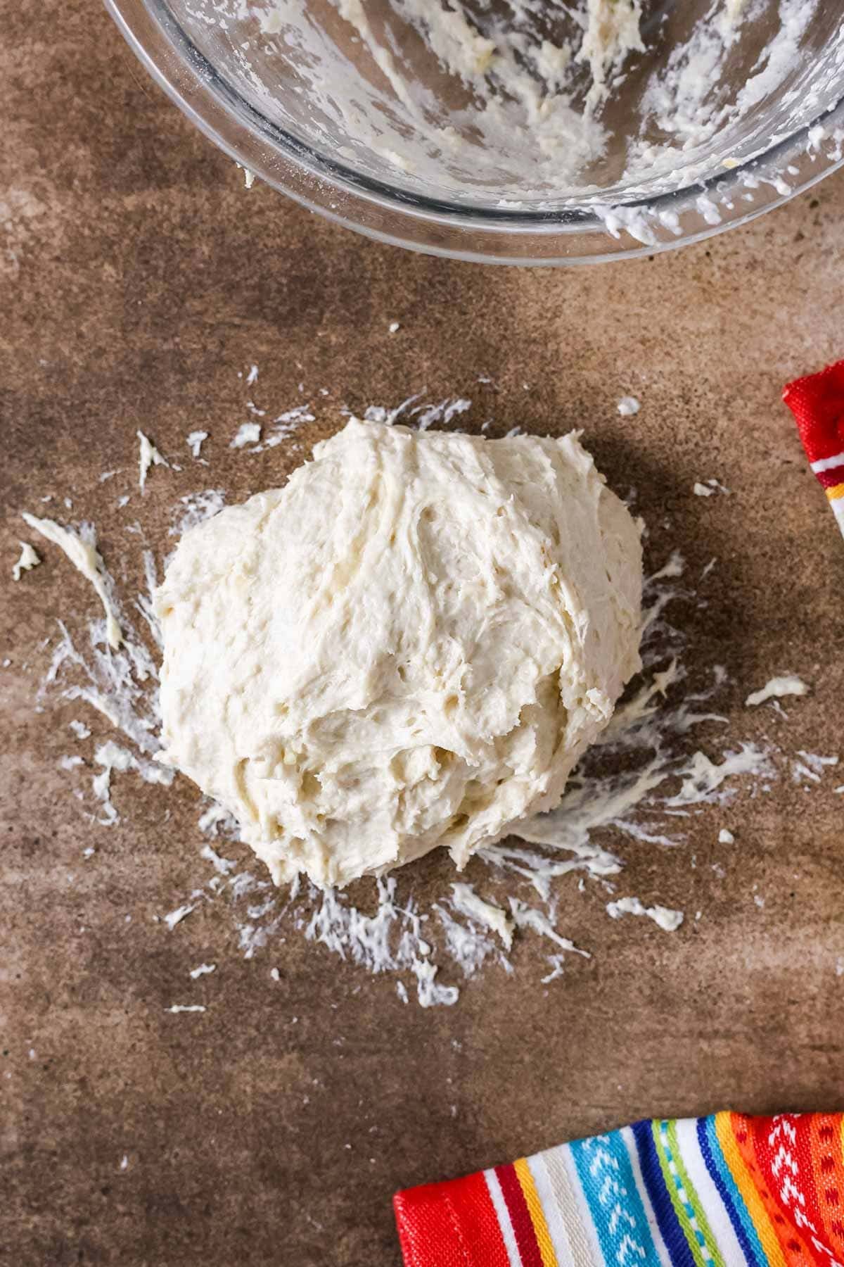 Dough that's been just worked together on a wood surface.