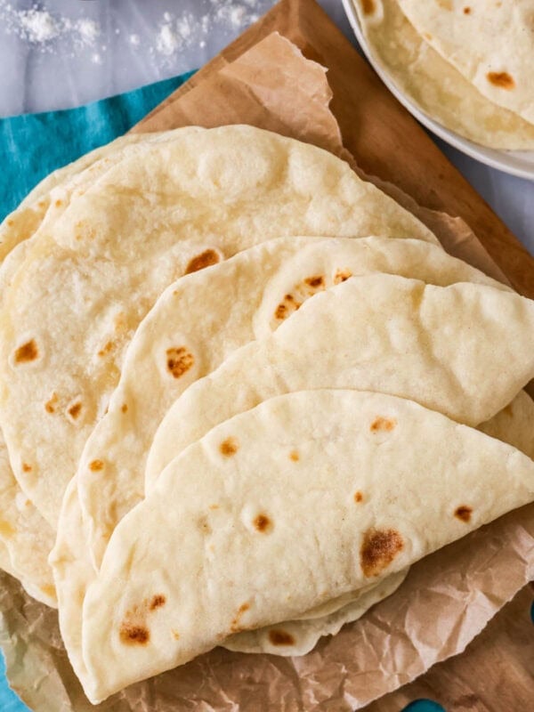 Pile of sourdough tortillas on a wood platter.