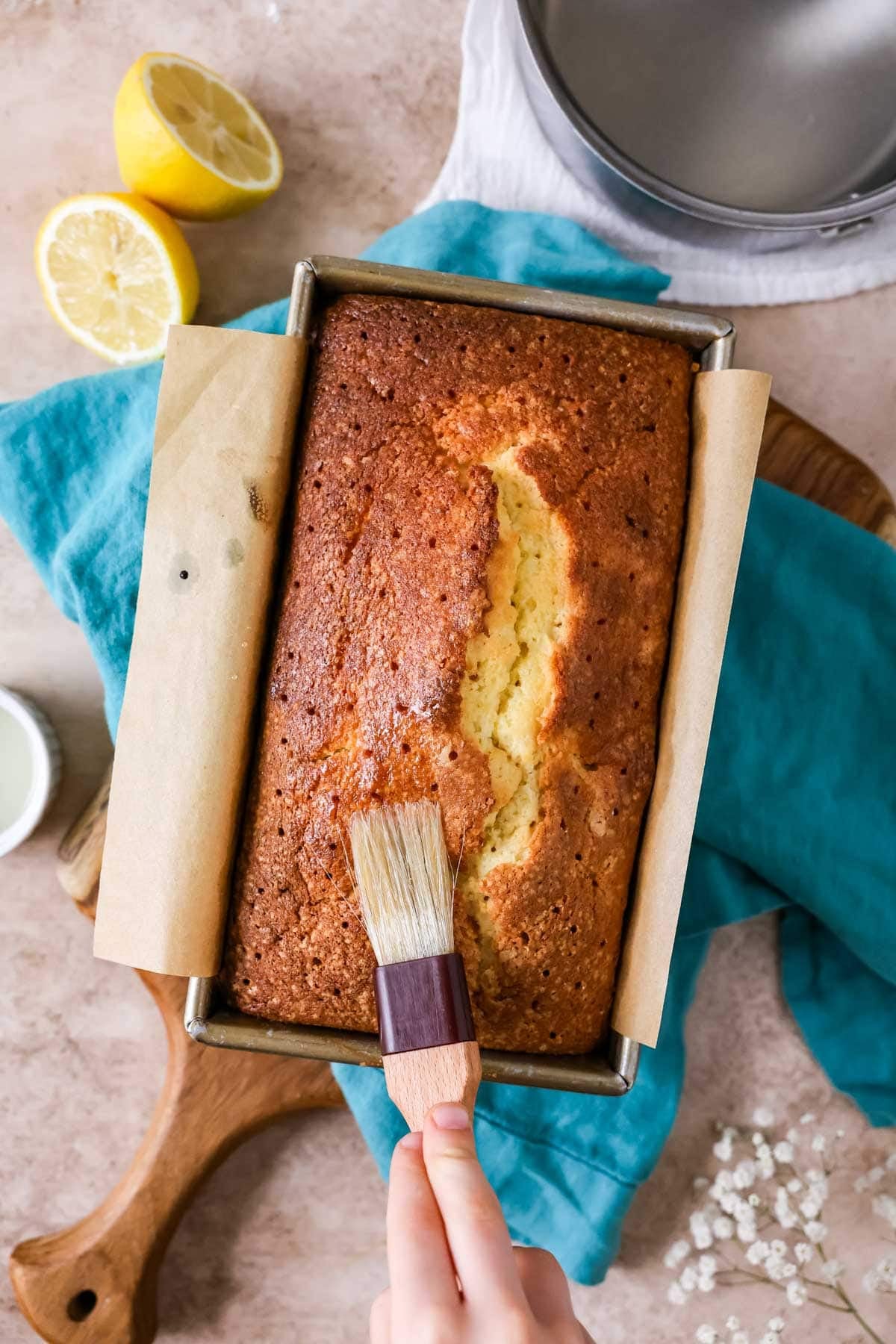 Brushing simple syrup over a lemon loaf before removing from the pan.