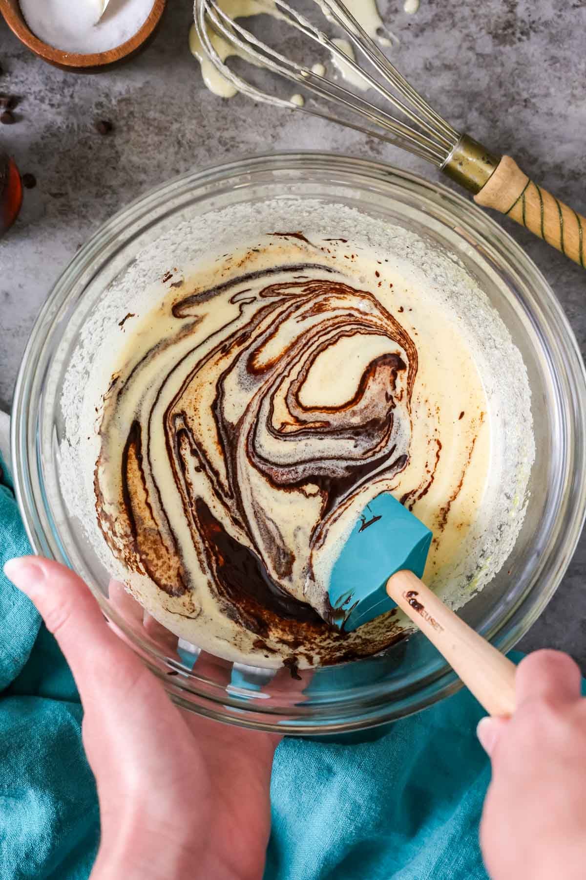 Folding bloomed cocoa powder and butter into a whisked egg and sugar mixture.