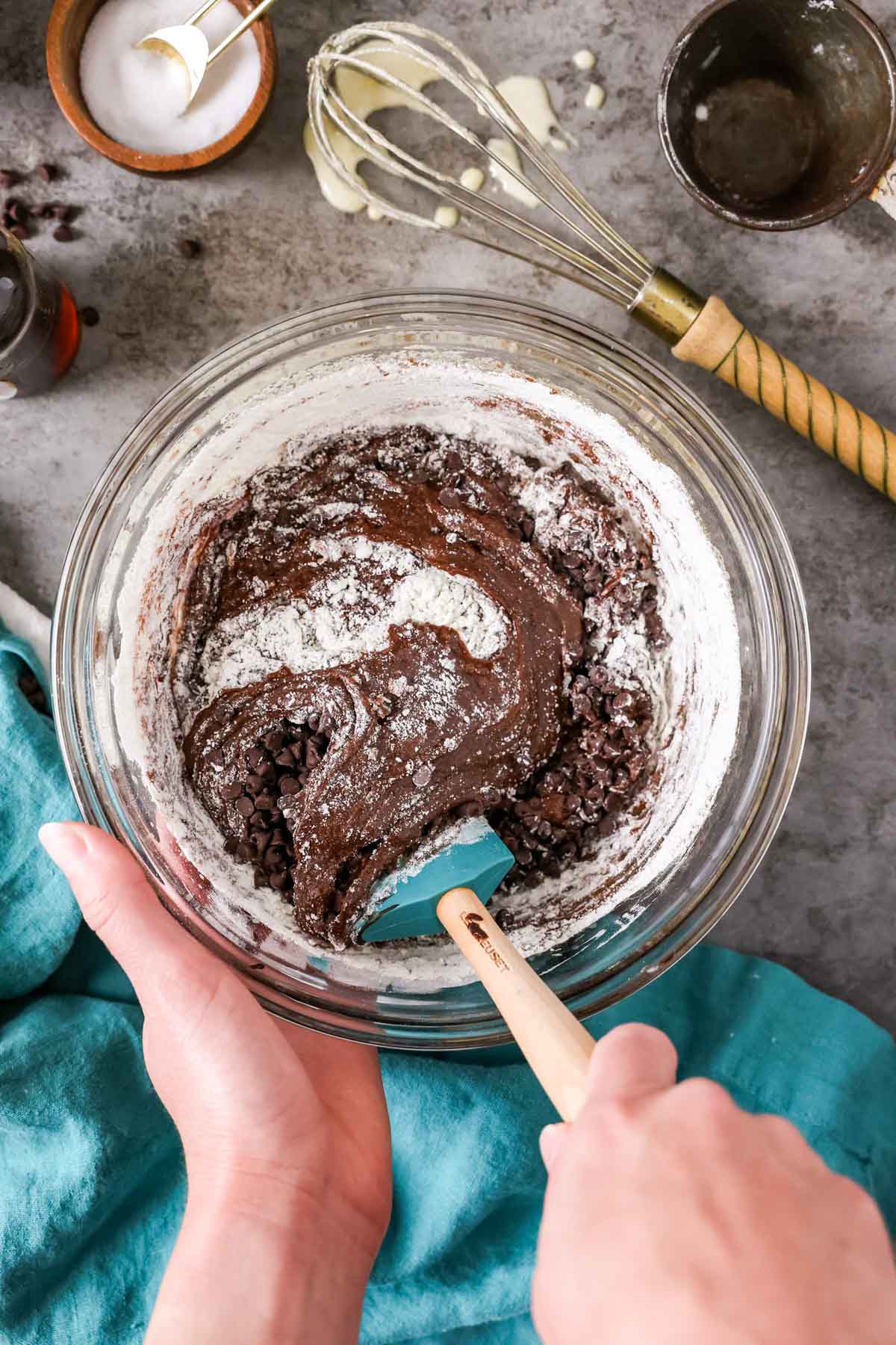 Gently folding flour into a chocolate batter for brownies.