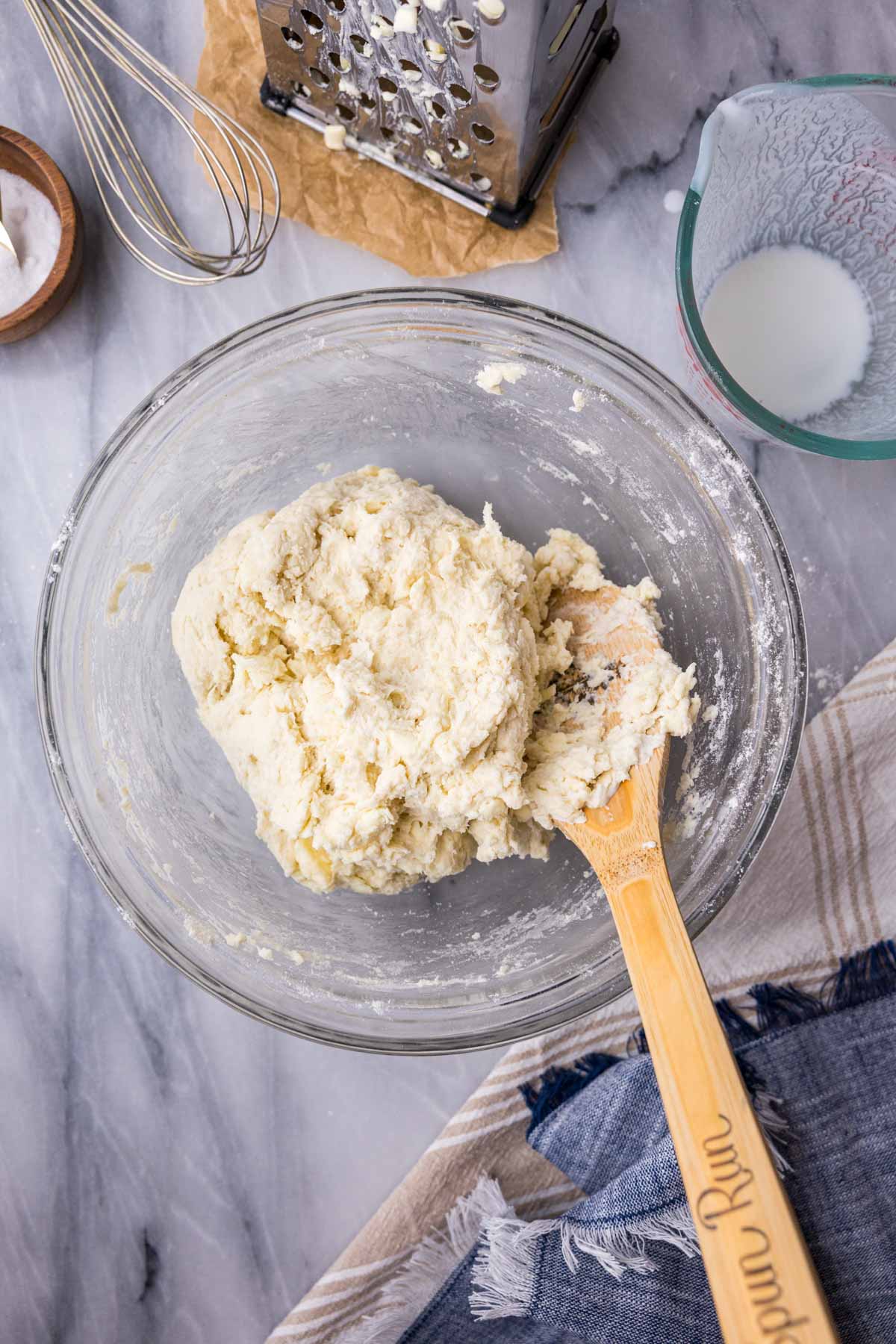 Overhead view of a shaggy biscuit dough in a bowl.