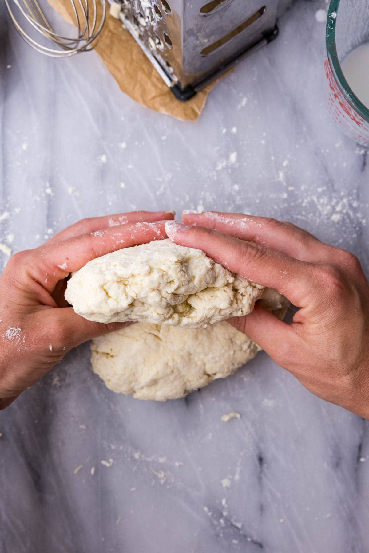 Hands laminating a biscuit dough for flaky layers.