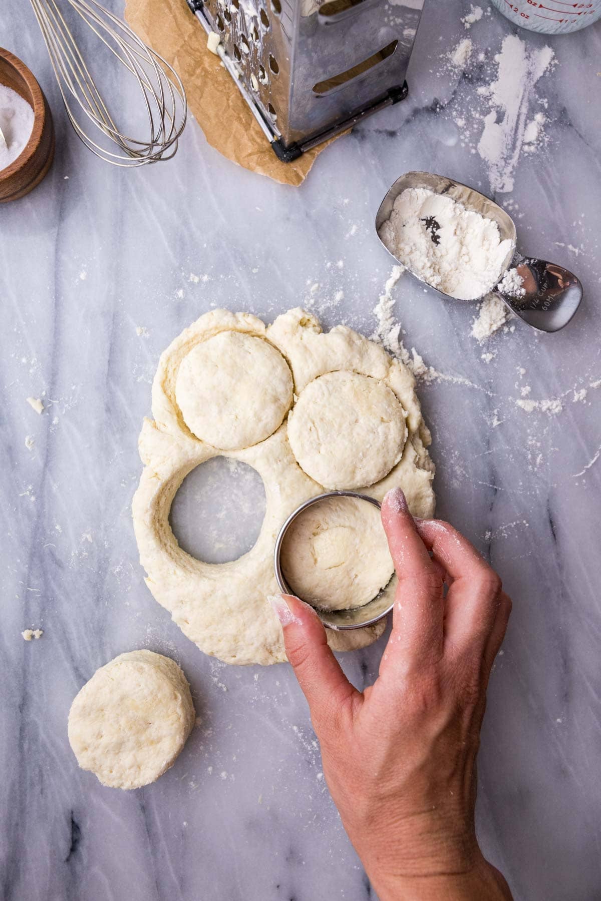 Cutting biscuits out of a dough with a biscuit cutter.