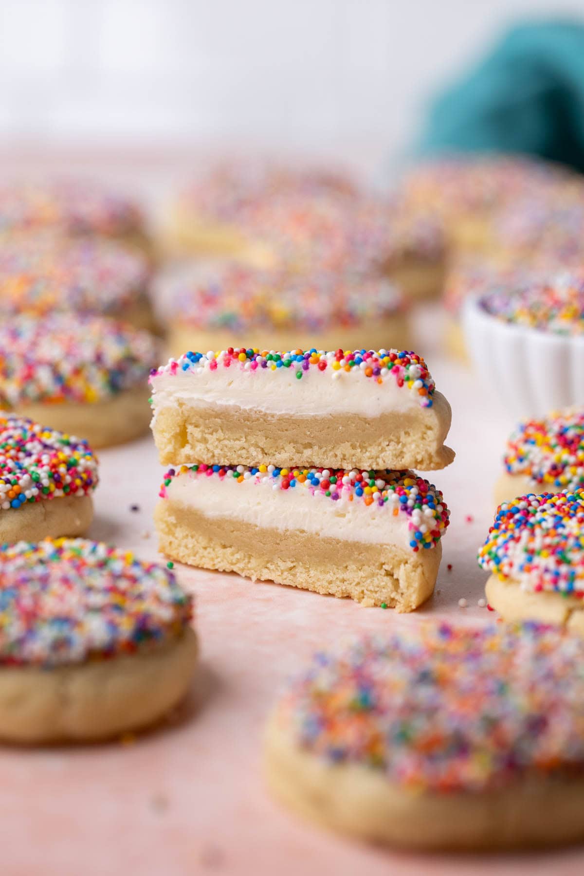 Cross section of a dot cake cookie made with a thick cookie base, vanilla frosting, and nonpareil sprinkles.