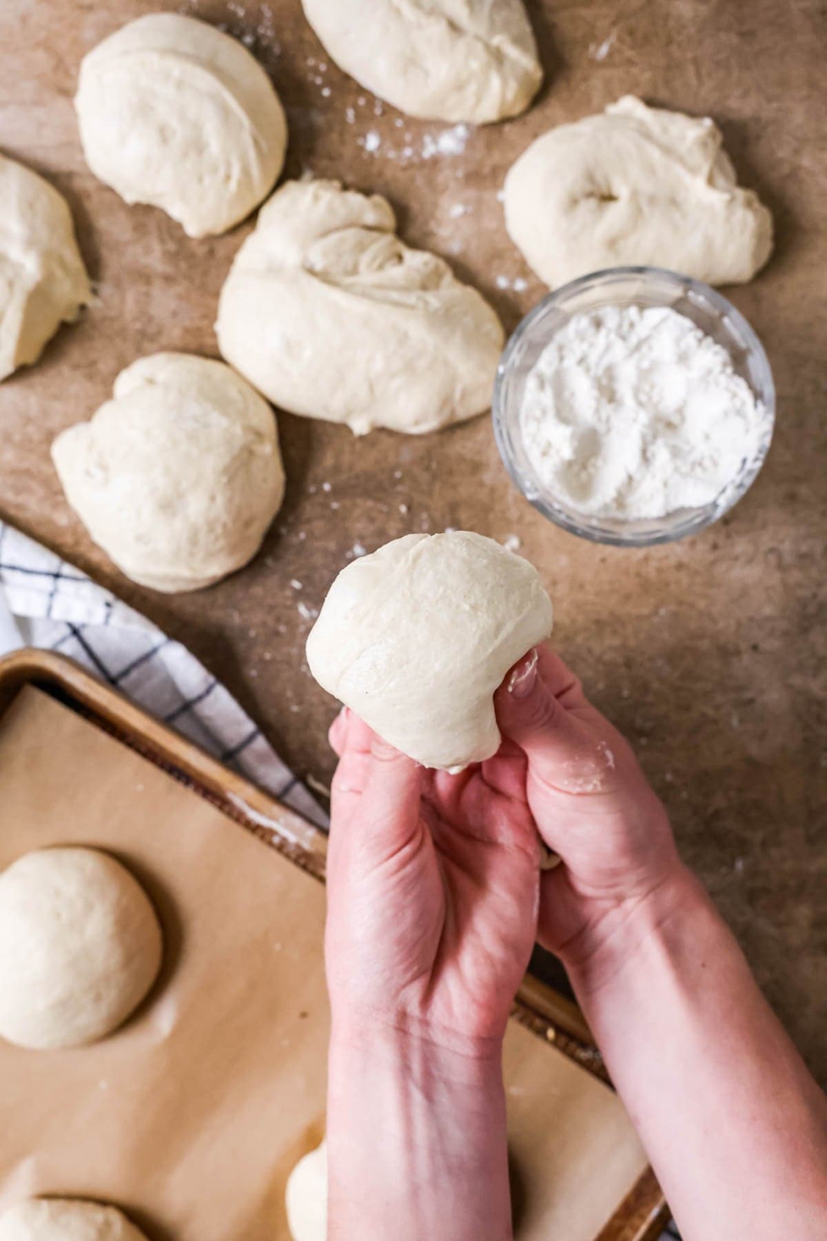 Hands forming a dough into round balls for burger buns.
