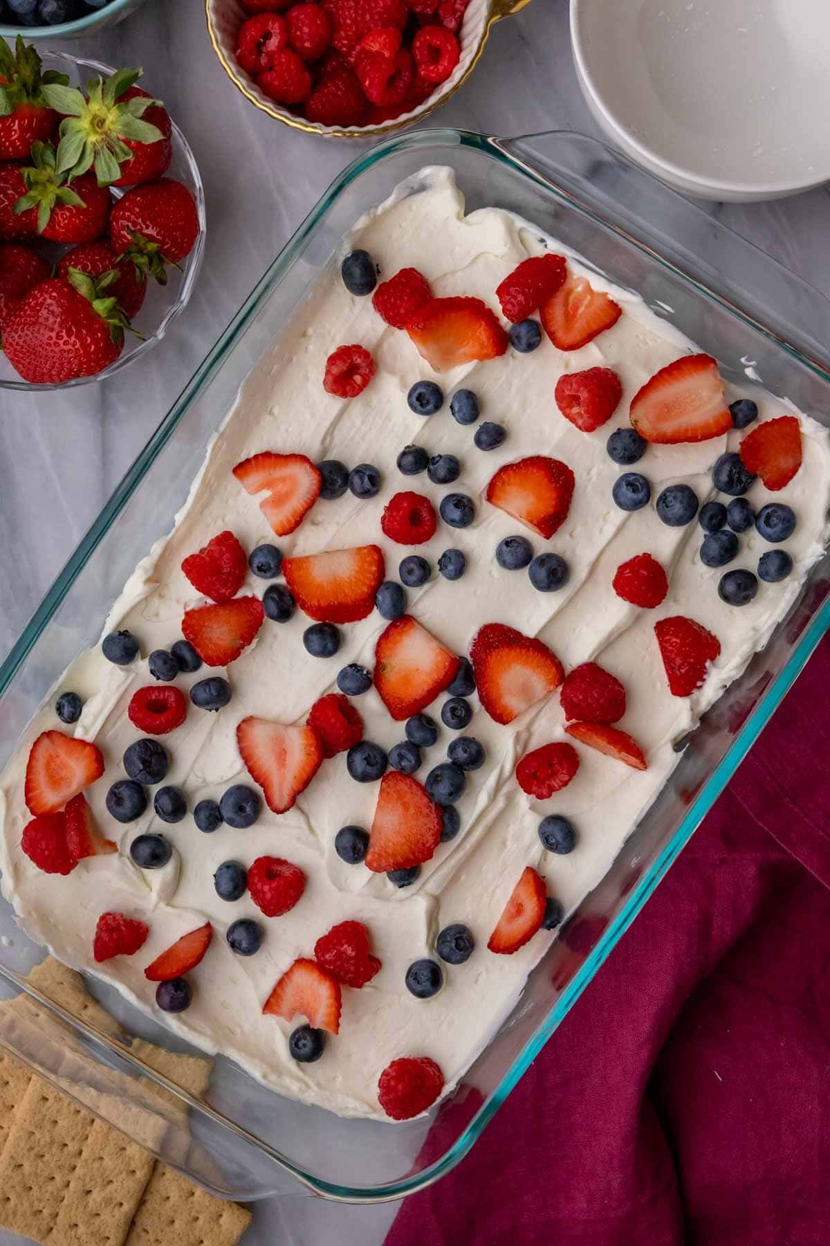 Layering berries over layers of cream cheese and graham crackers.