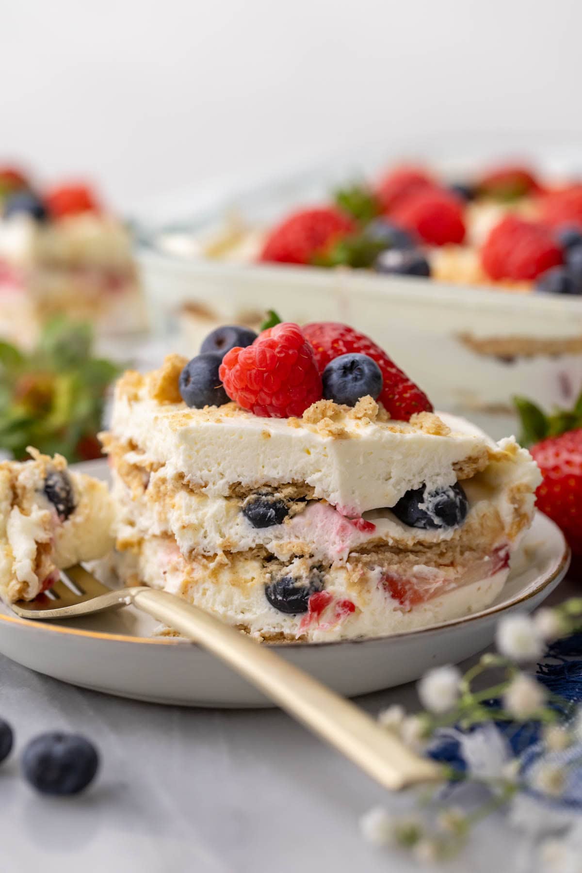 Bite missing from a no-bake berry and cream layer cake on a plate.