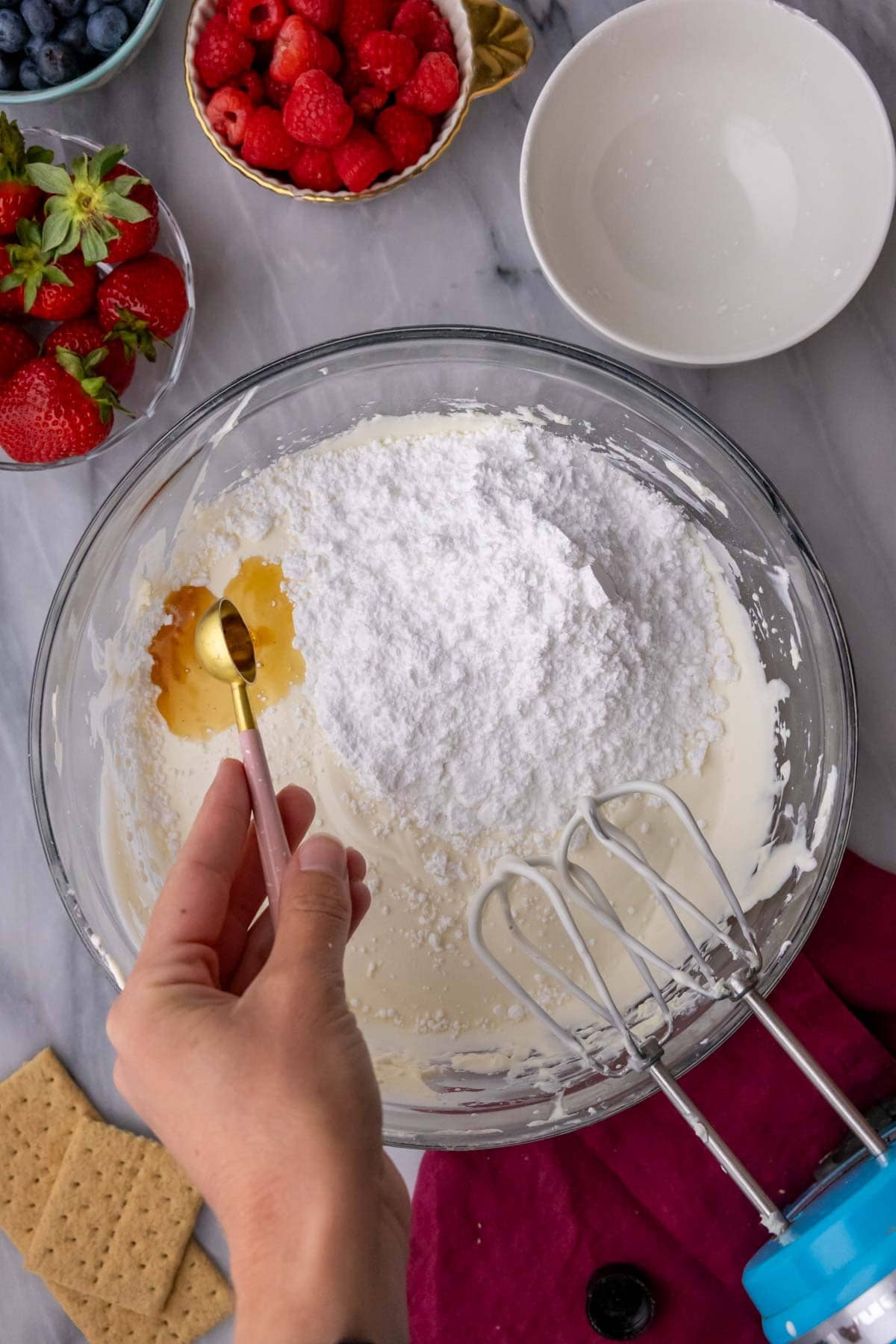 Adding vanilla and powdered sugar to a heavy cream and cream cheese mixture.