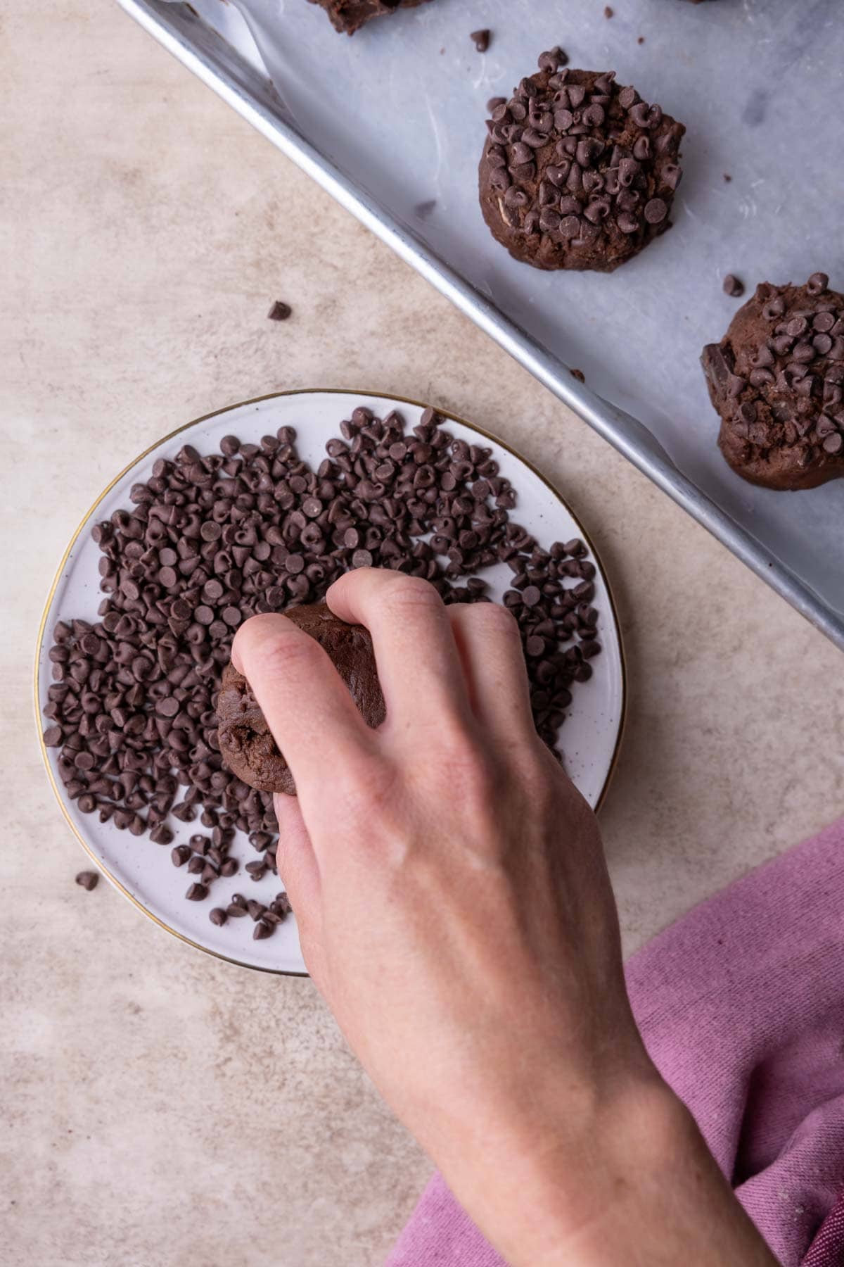 Rolling a chocolate cookie dough ball in mini chocolate chips.