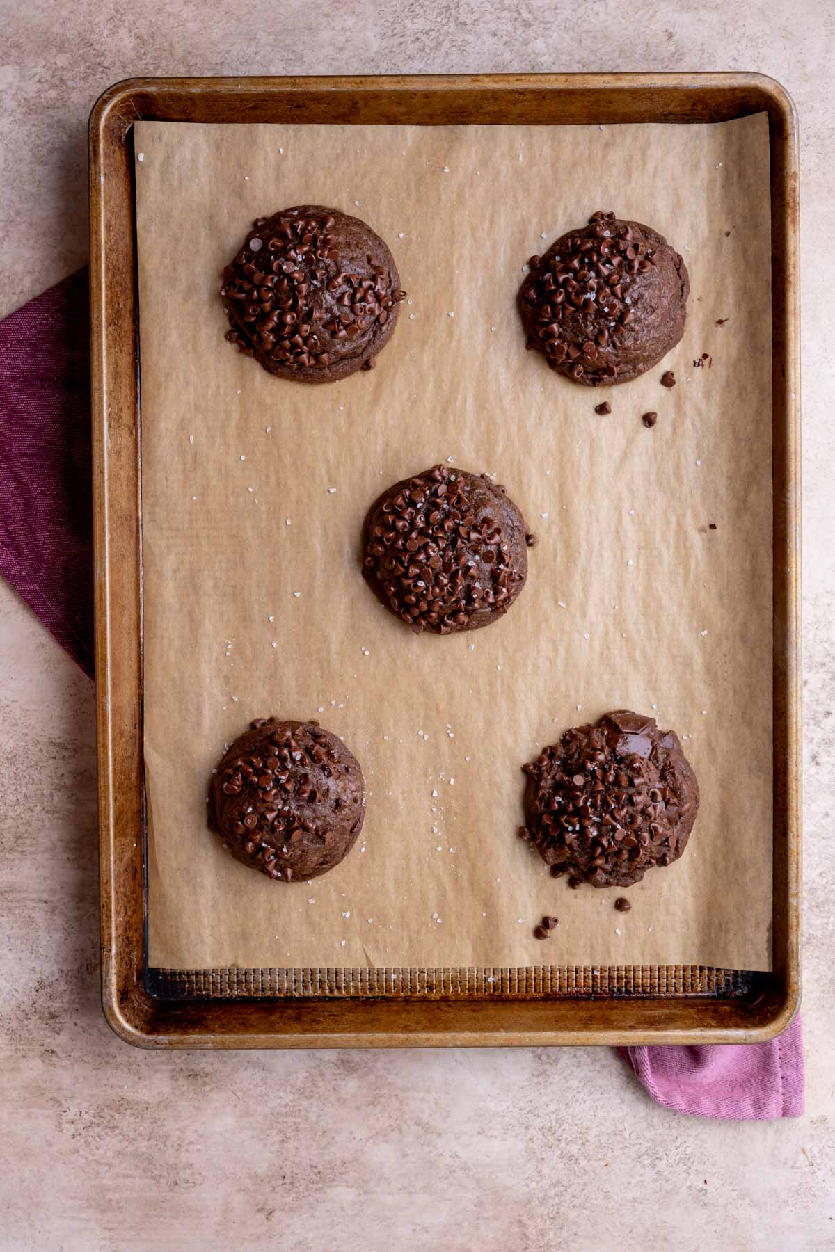 Overhead view of thick, bakery style double chocolate cookies on a baking sheet after baking.