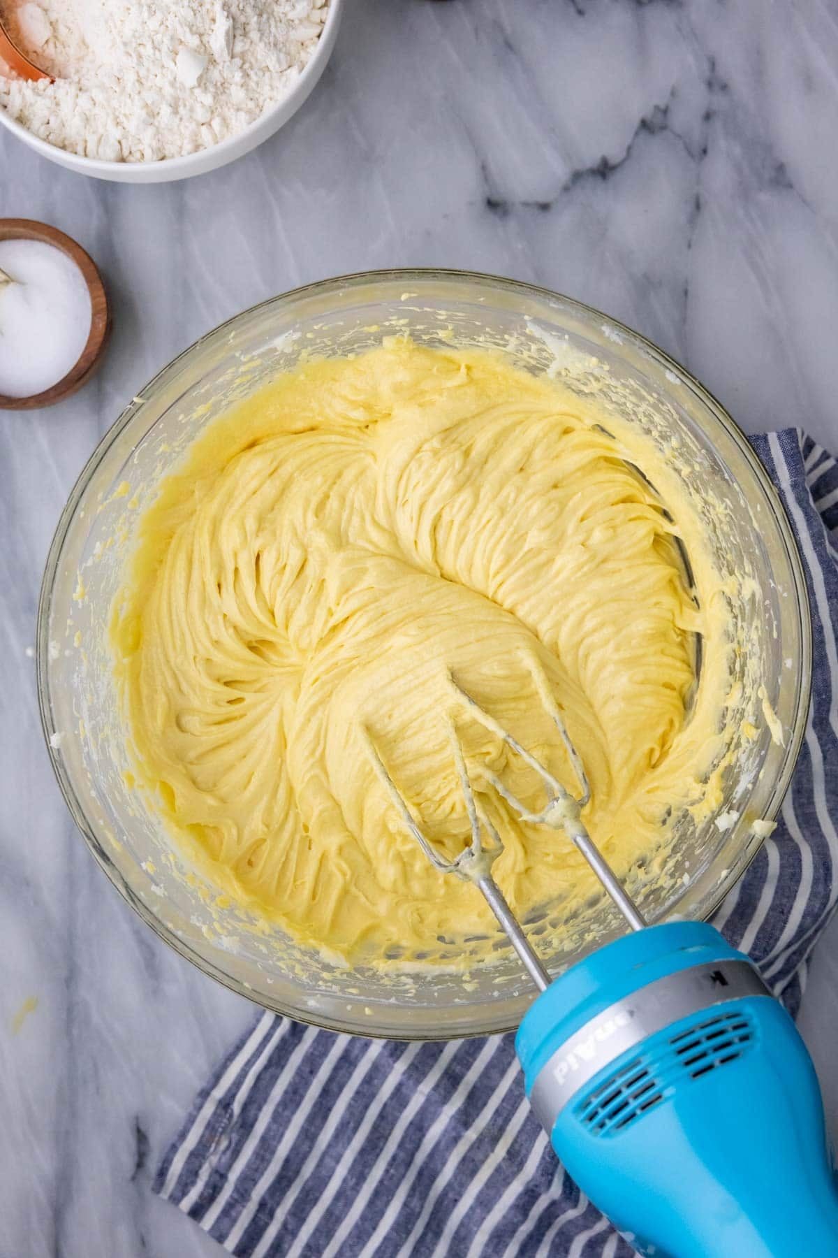 Silky smooth pound cake batter in glass mixing bowl on marble.