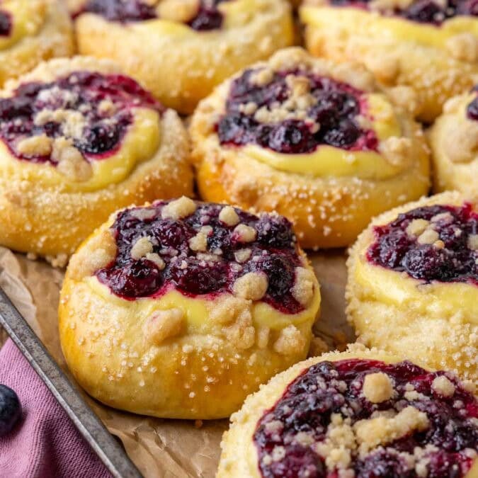 Close-up view of blueberry cheesecake buns topped with streusel and coarse sugar.