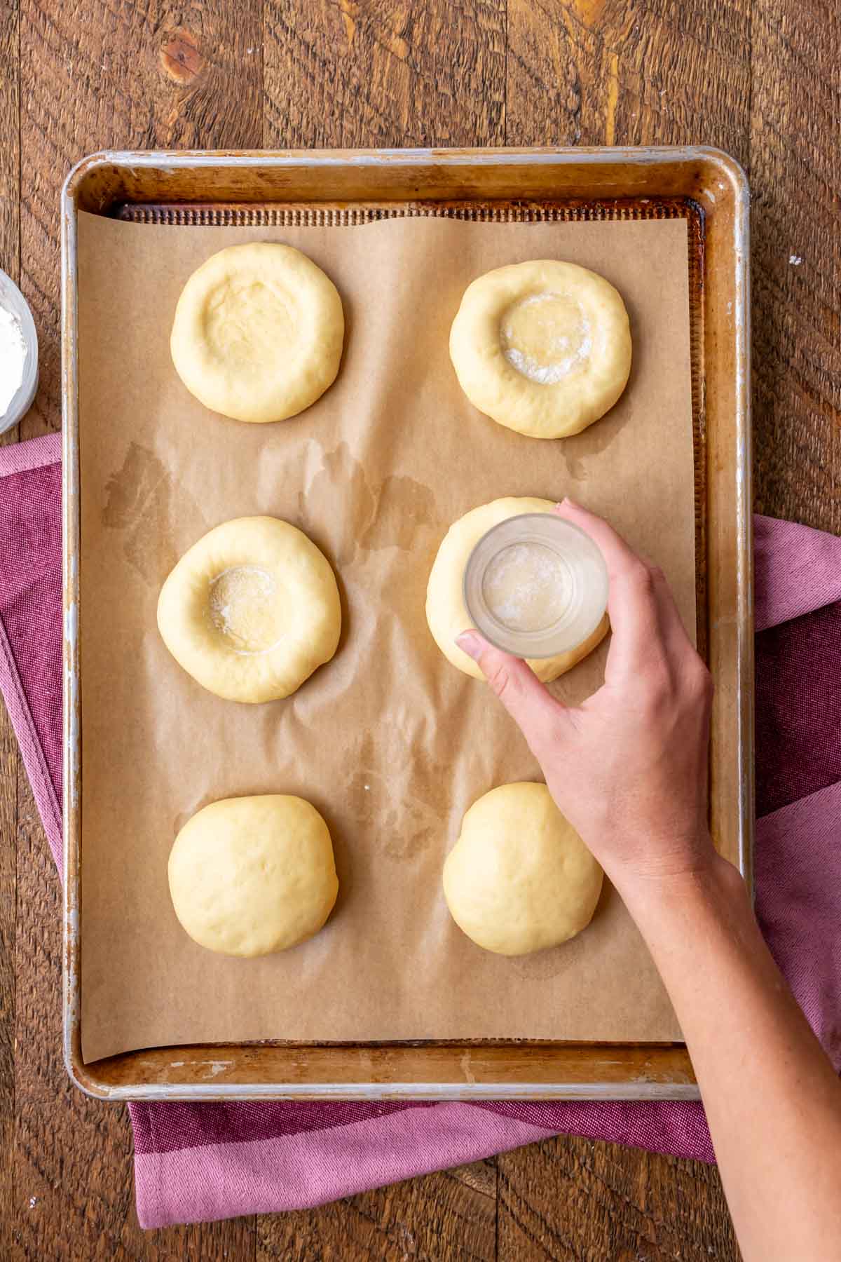 Glass pressing an indent into buns for a filling.