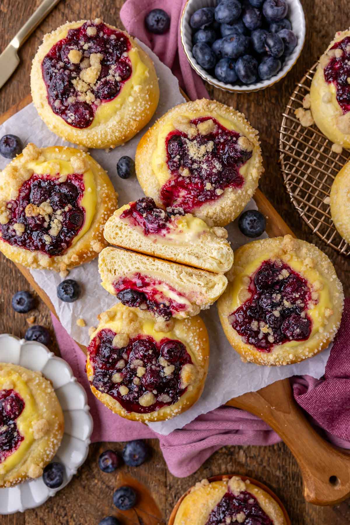 Overhead view of blueberry cheesecake buns with the centermost bun cut in half and stacked to show the texture.