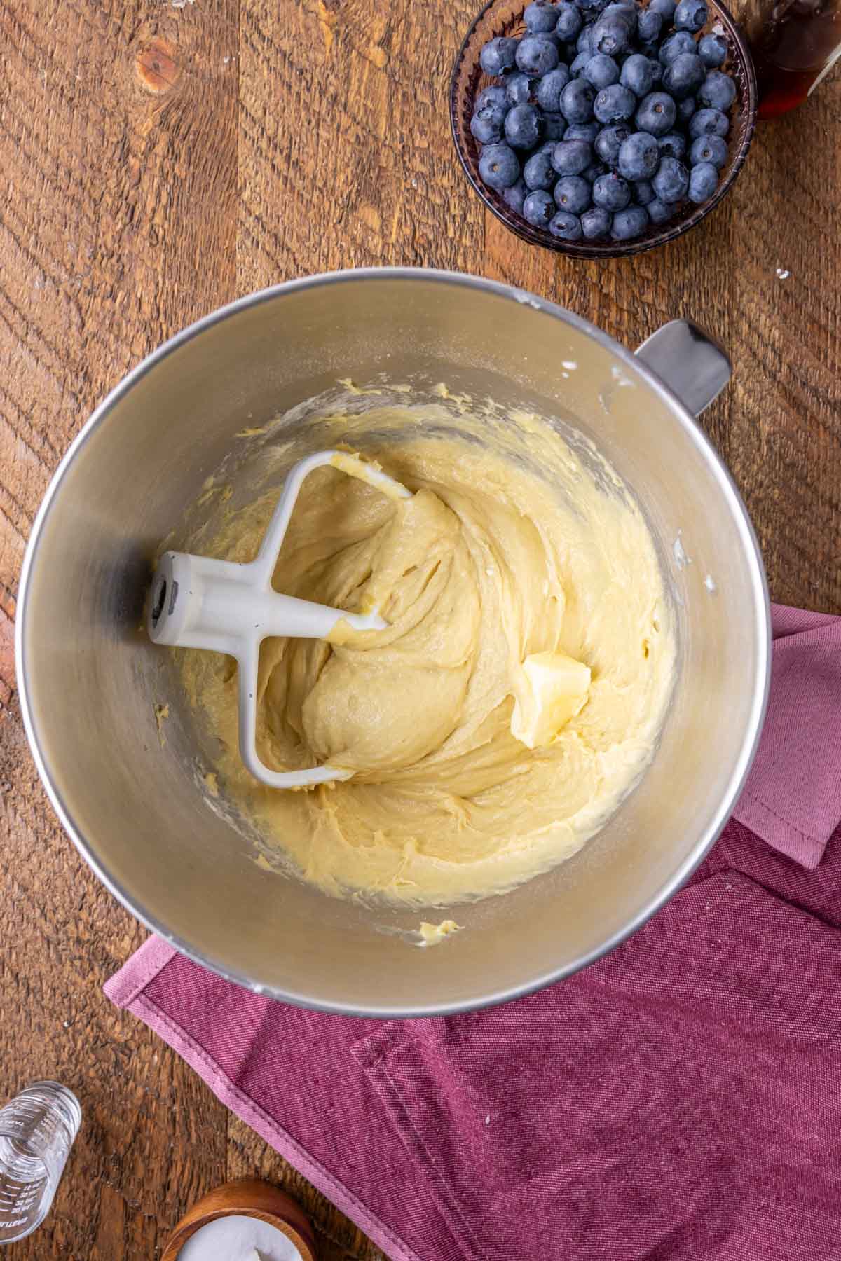 Overhead view of butter being added to a yeast dough in a mixer bowl.