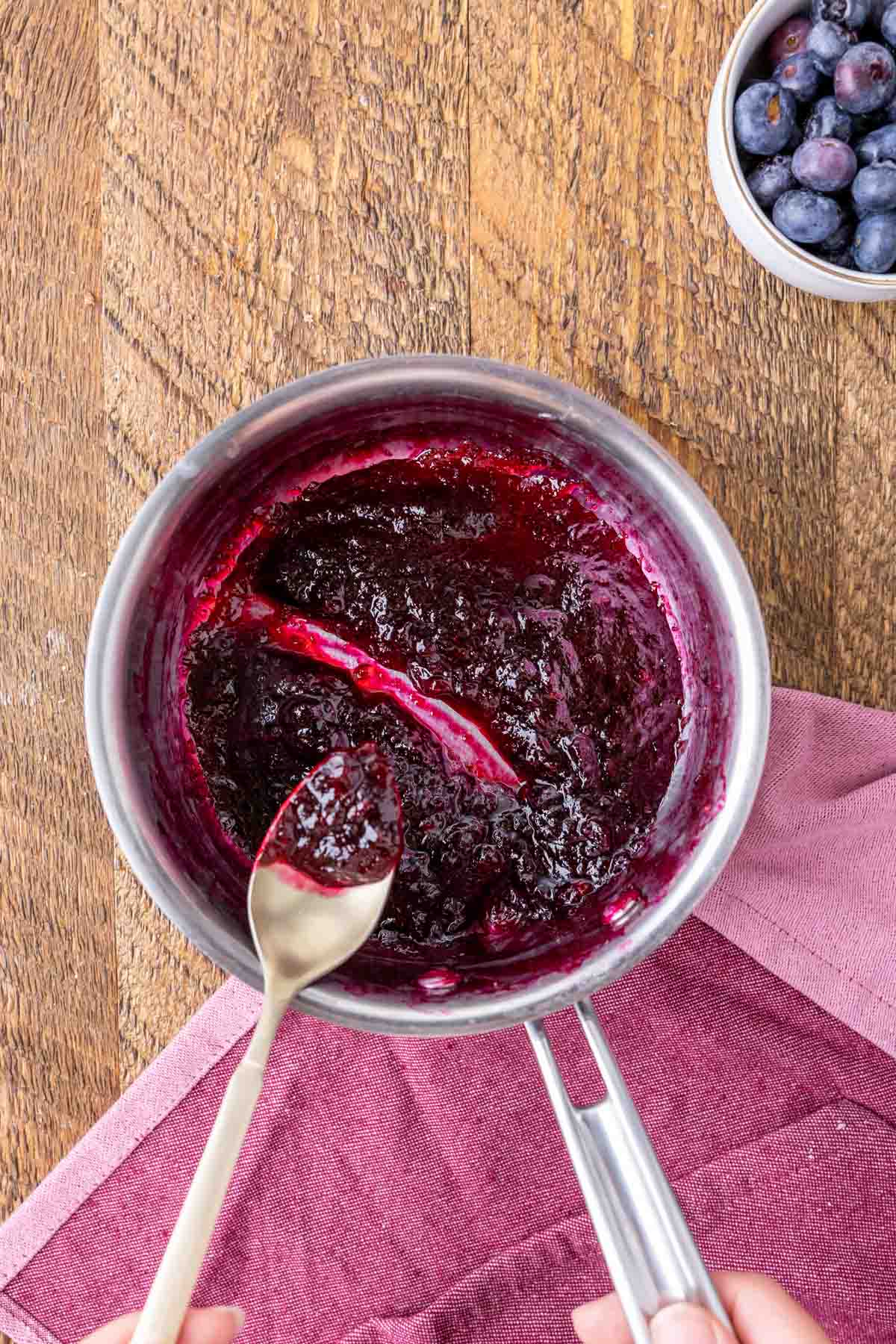 Overhead view of blueberry sauce in a pot after thickening.