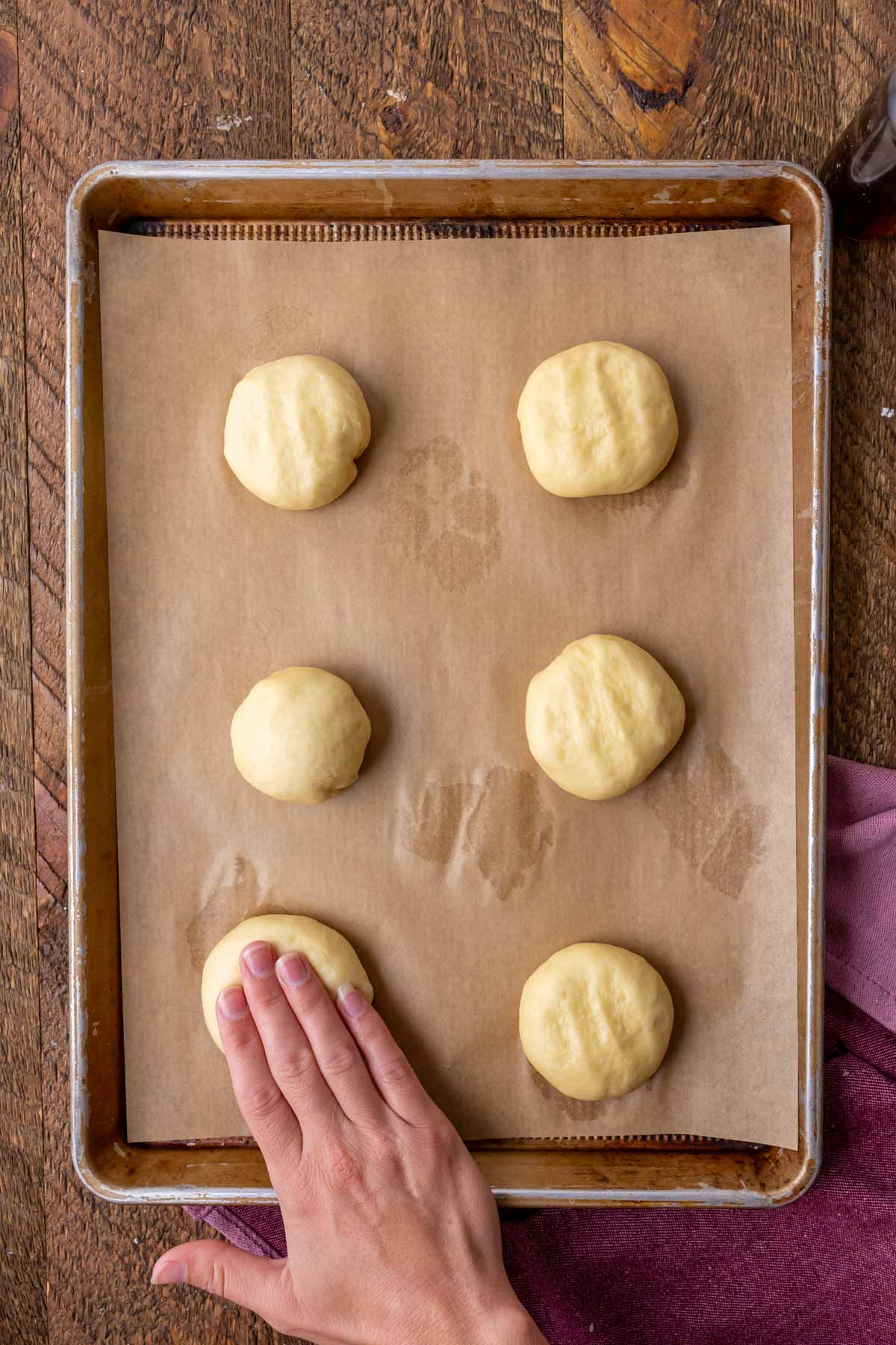 Hands pressing dough balls into flat discs.