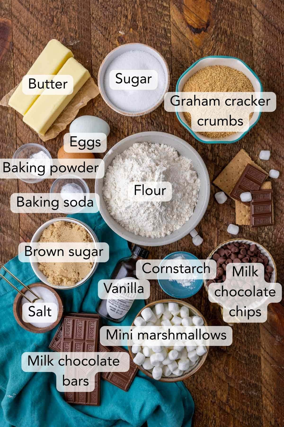 overhead view of ingredients for smores cookies including graham cracker crumbs, hershey bars, marshmallows, flour, and more