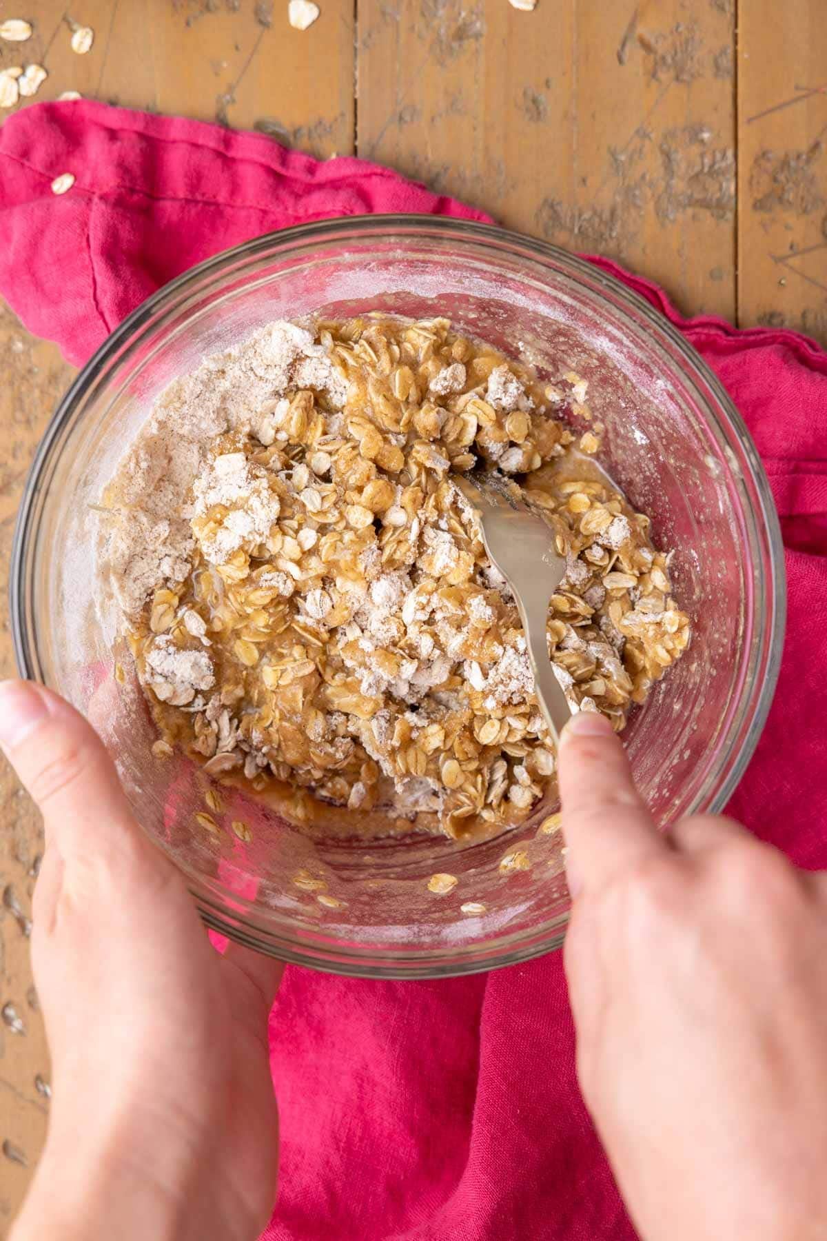 Using a gold fork to claw butter into a flour, sugar, and oat mixture for an easy apple crisp topping with oats.