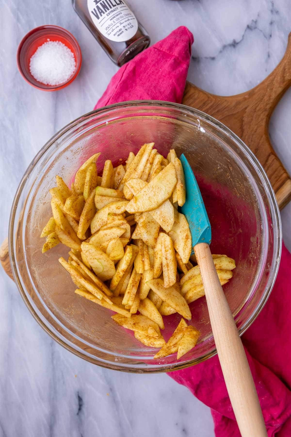 Overhead view of sliced apples tossed with sugar and cinnamon in a bowl.