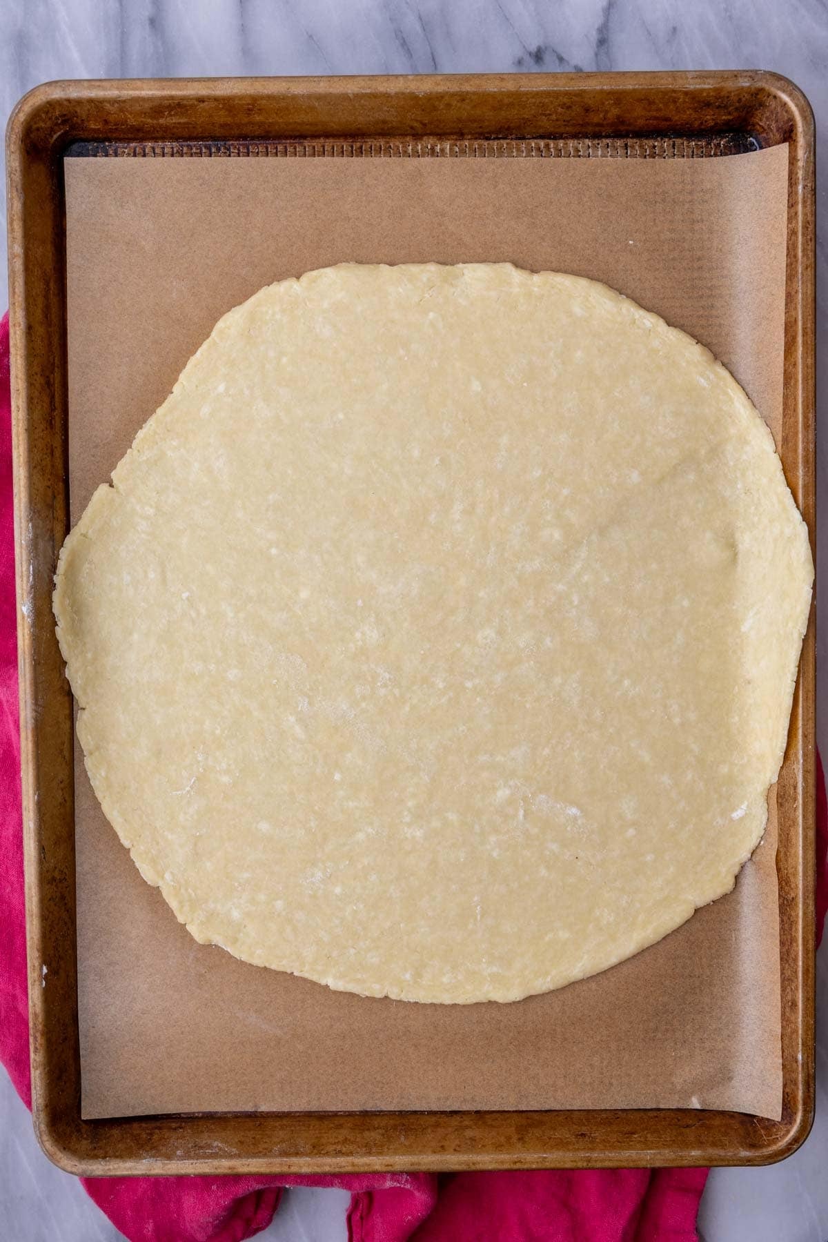 Overhead view of a pie crust rolled out on a baking sheet.