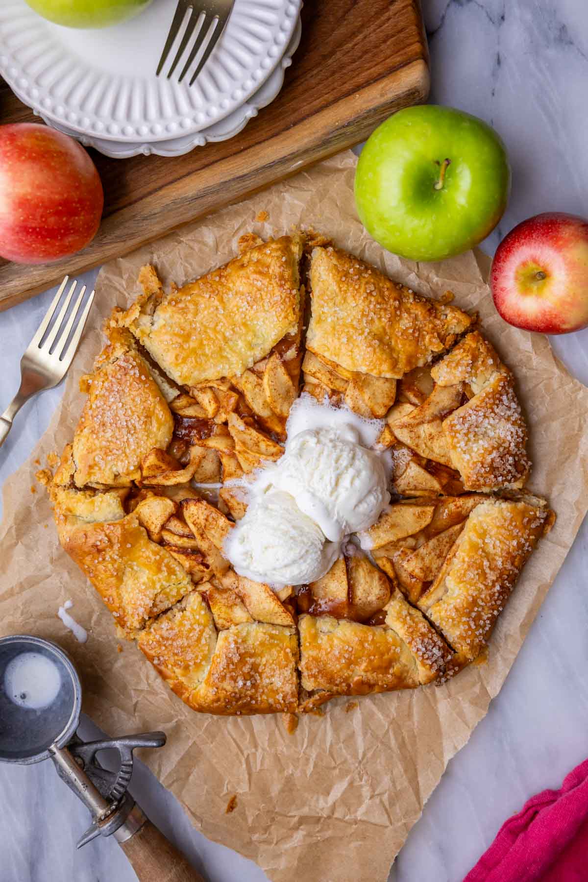 Overhead view of a golden brown and flaky apple galette topped with vanilla ice cream.