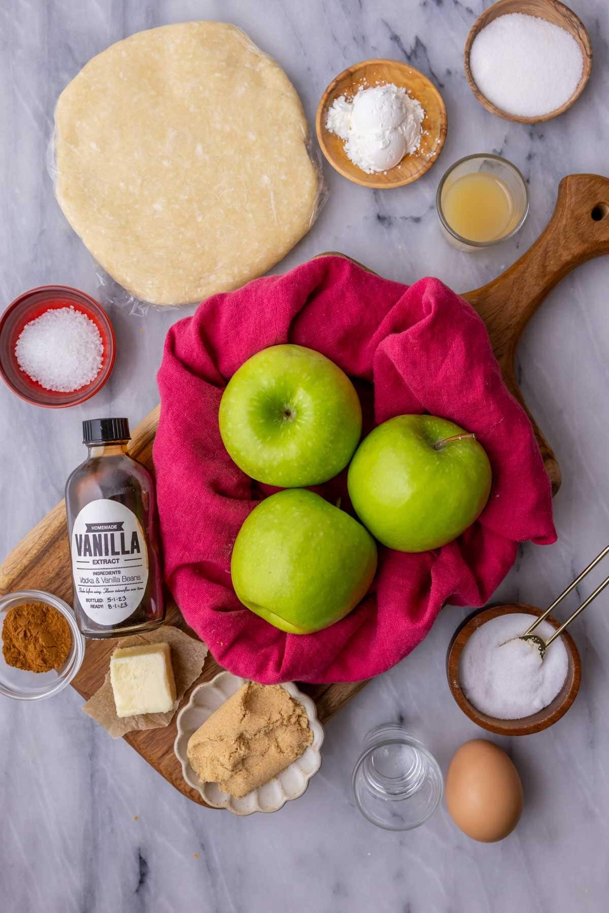 Overhead view of ingredients including pie dough, apples, brown sugar, and more.