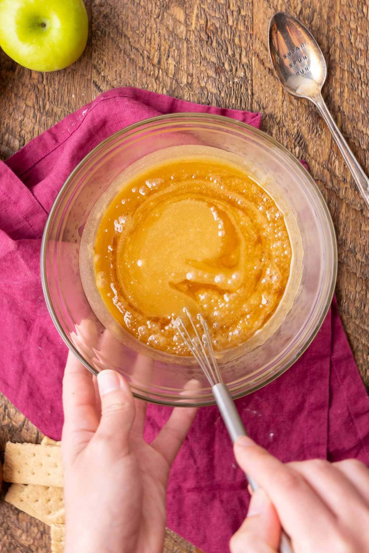 Overhead view of bubbly caramel being stirred in a bowl.