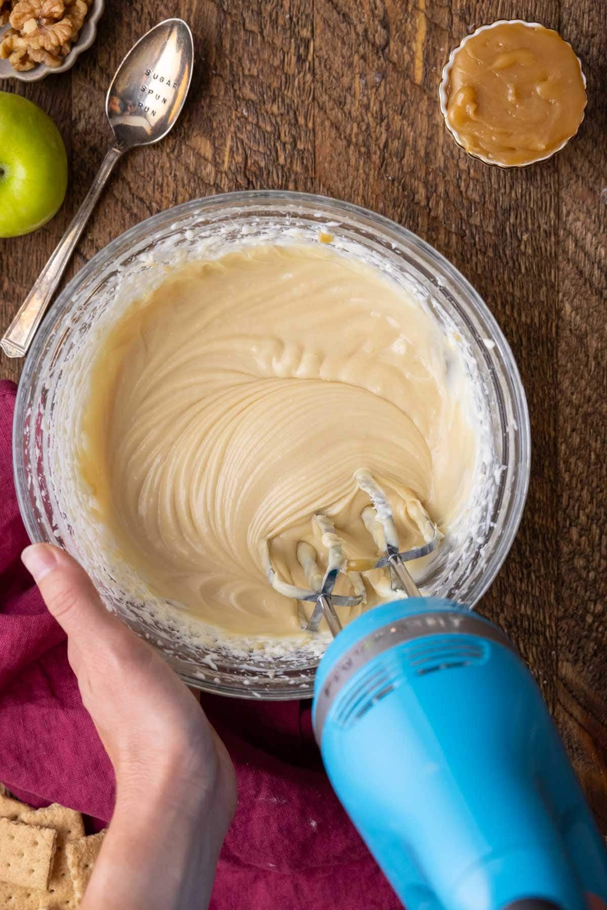 Overhead view of a caramel and cream cheese mixture in a bowl.
