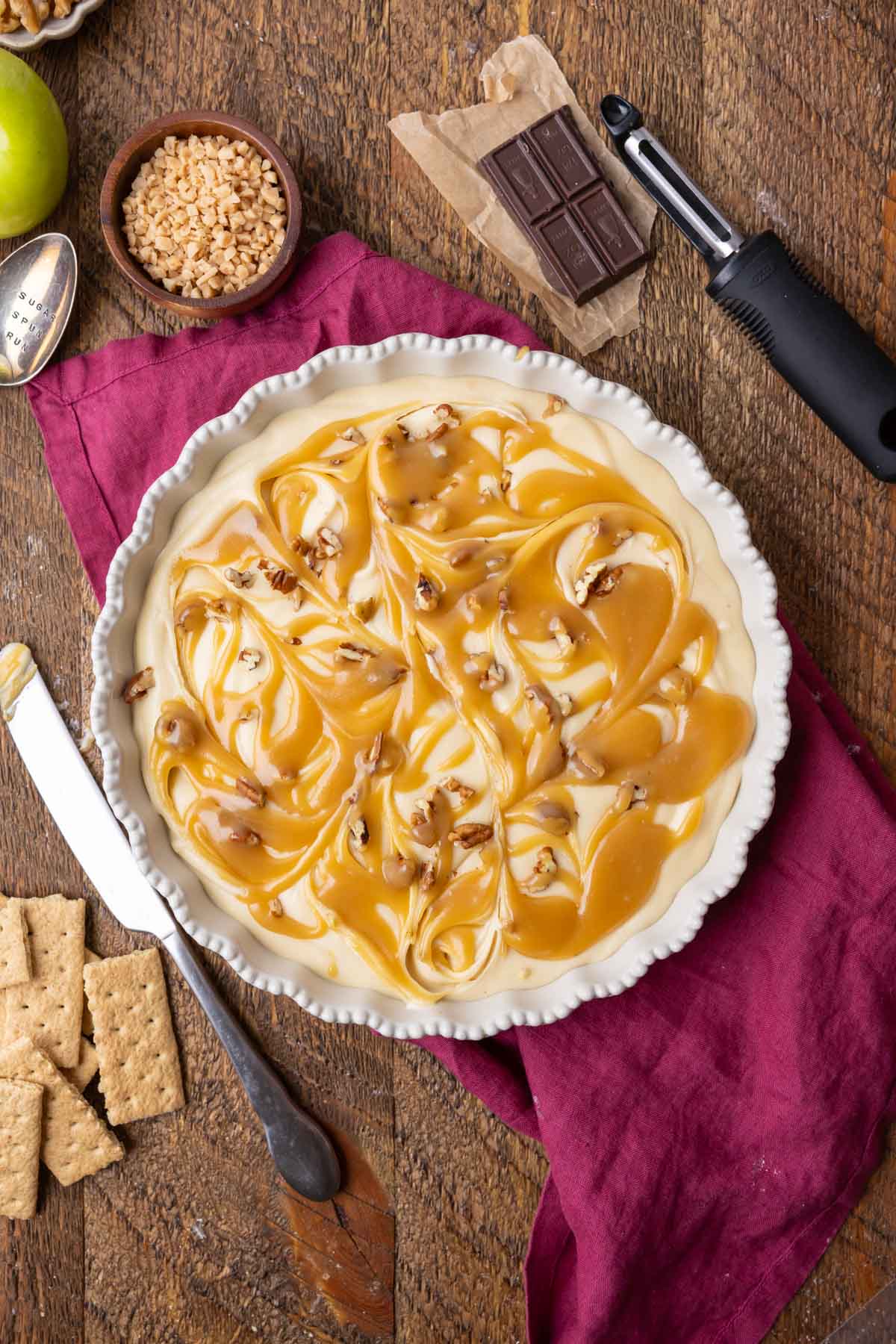 Overhead view of caramel apple cheesecake dip topped with caramel and pecans.