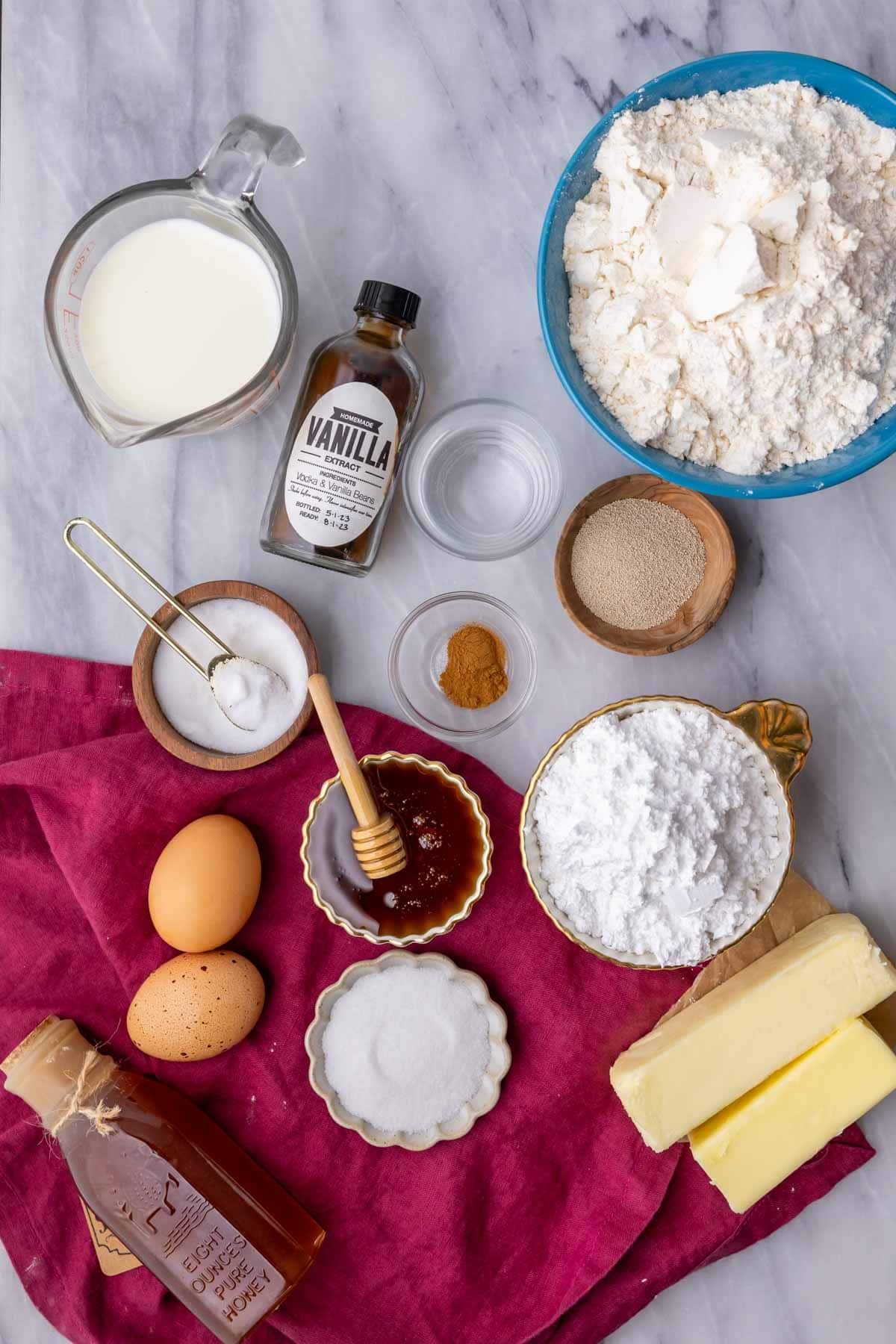 Overhead view of ingredients including honey, bread flour, butter, yeast and more.