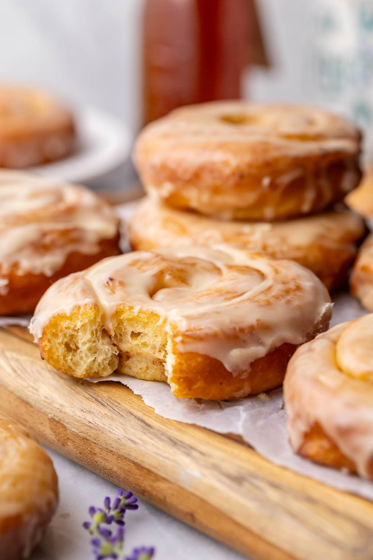 Bite missing from a homemade honey bun with more buns in the background.