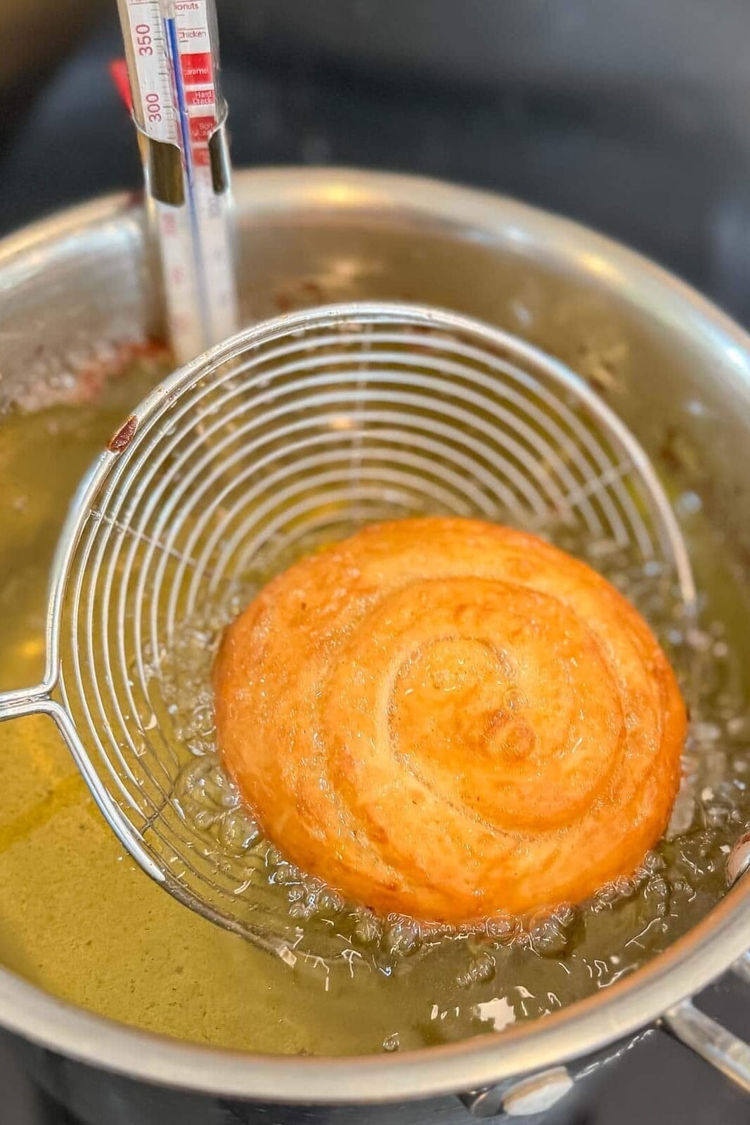 Frying spider pulling a golden brown honey bun out of the hot oil.