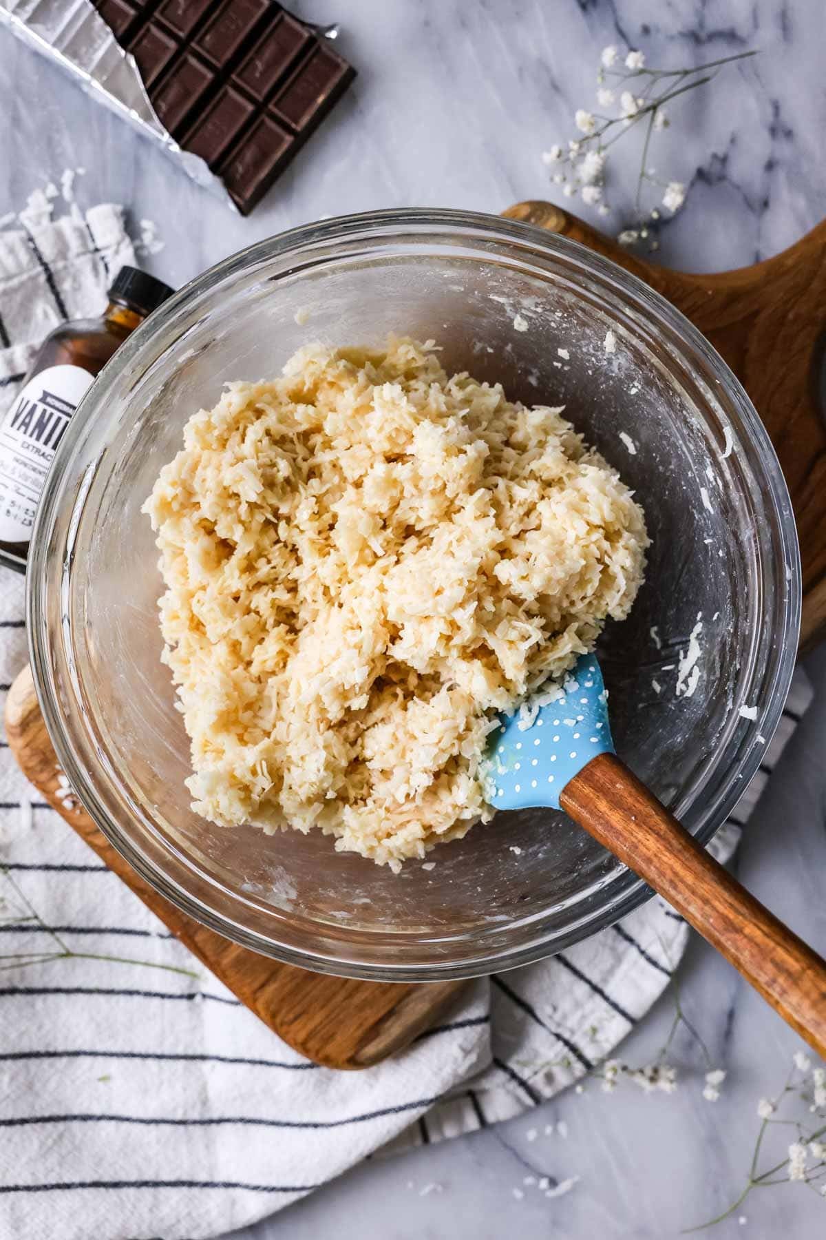 Overhead view of coconut stirred together with condensed milk, extracts, and salt.