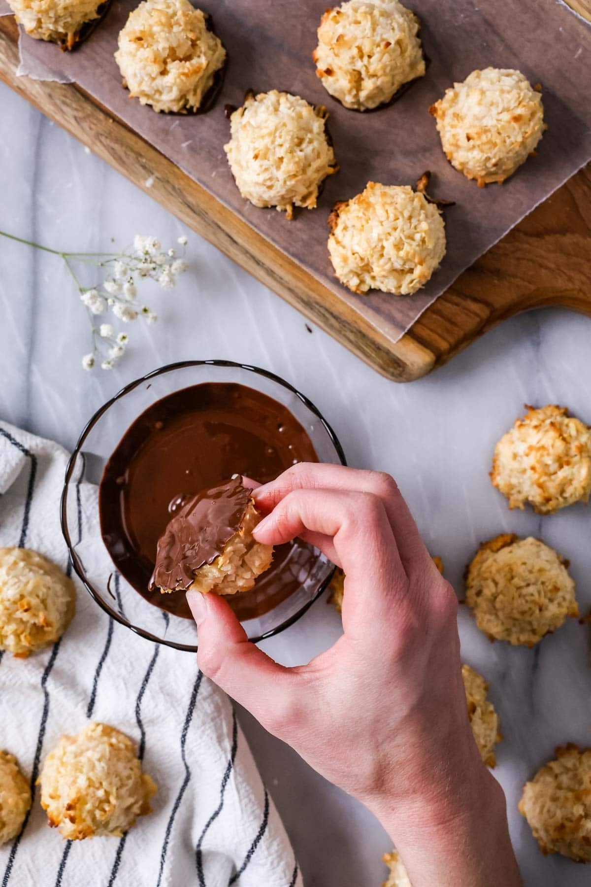 Dipping coconut macaroons in melted chocolate after baking.