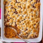 Overhead view of sweet potato casserole in a white dish with a spoon in the dish.