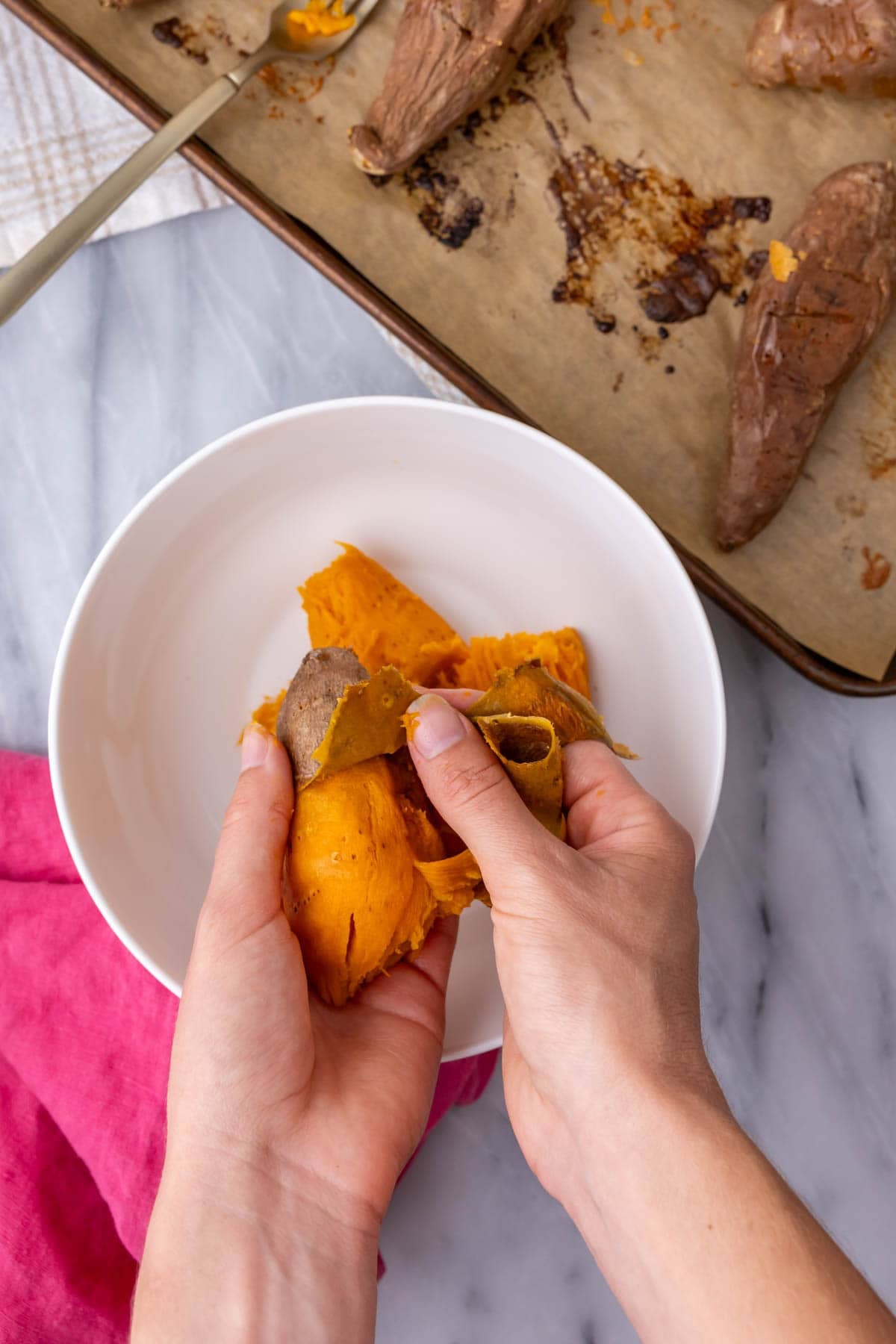 Peeling the skin off a roasted sweet potato to make sweet potato casserole.