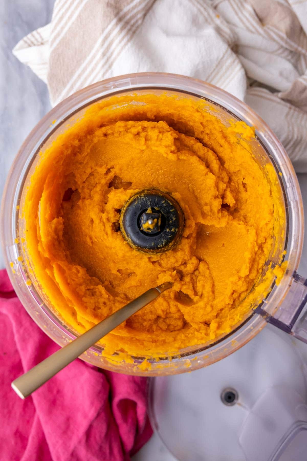 Pureed roasted sweet potatoes in the basin of a food processor.