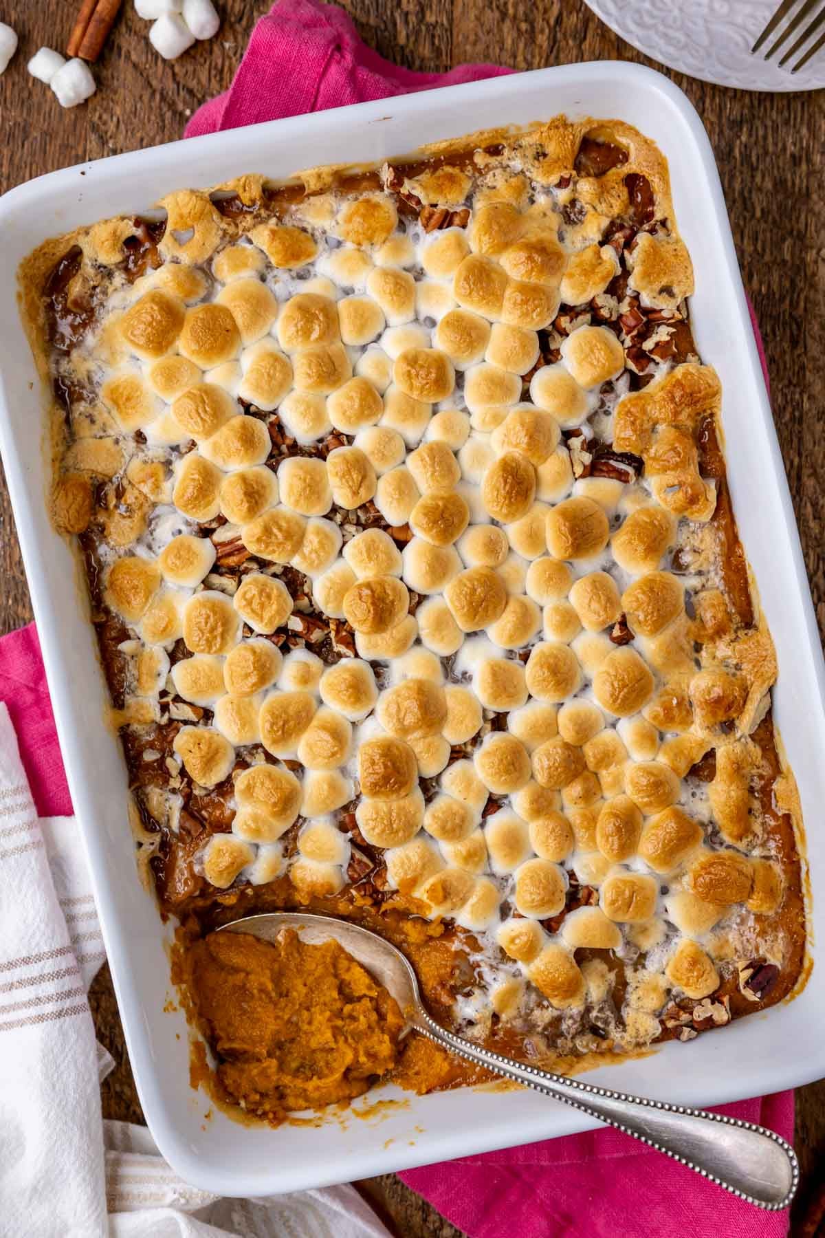 Overhead of creamy sweet potato casserole in a white dish on pink linen.