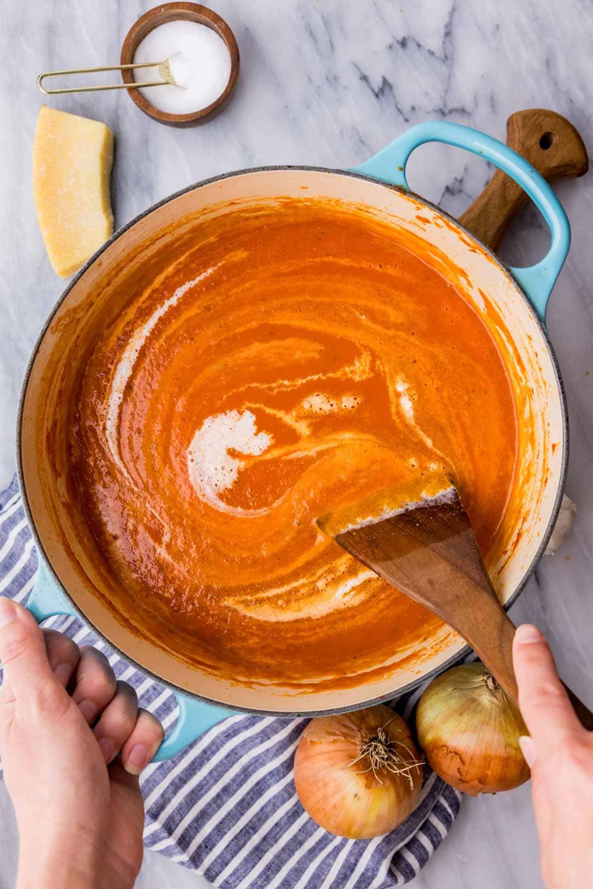 Stirring cream into tomato soup, the color lightens from deep red to orange.