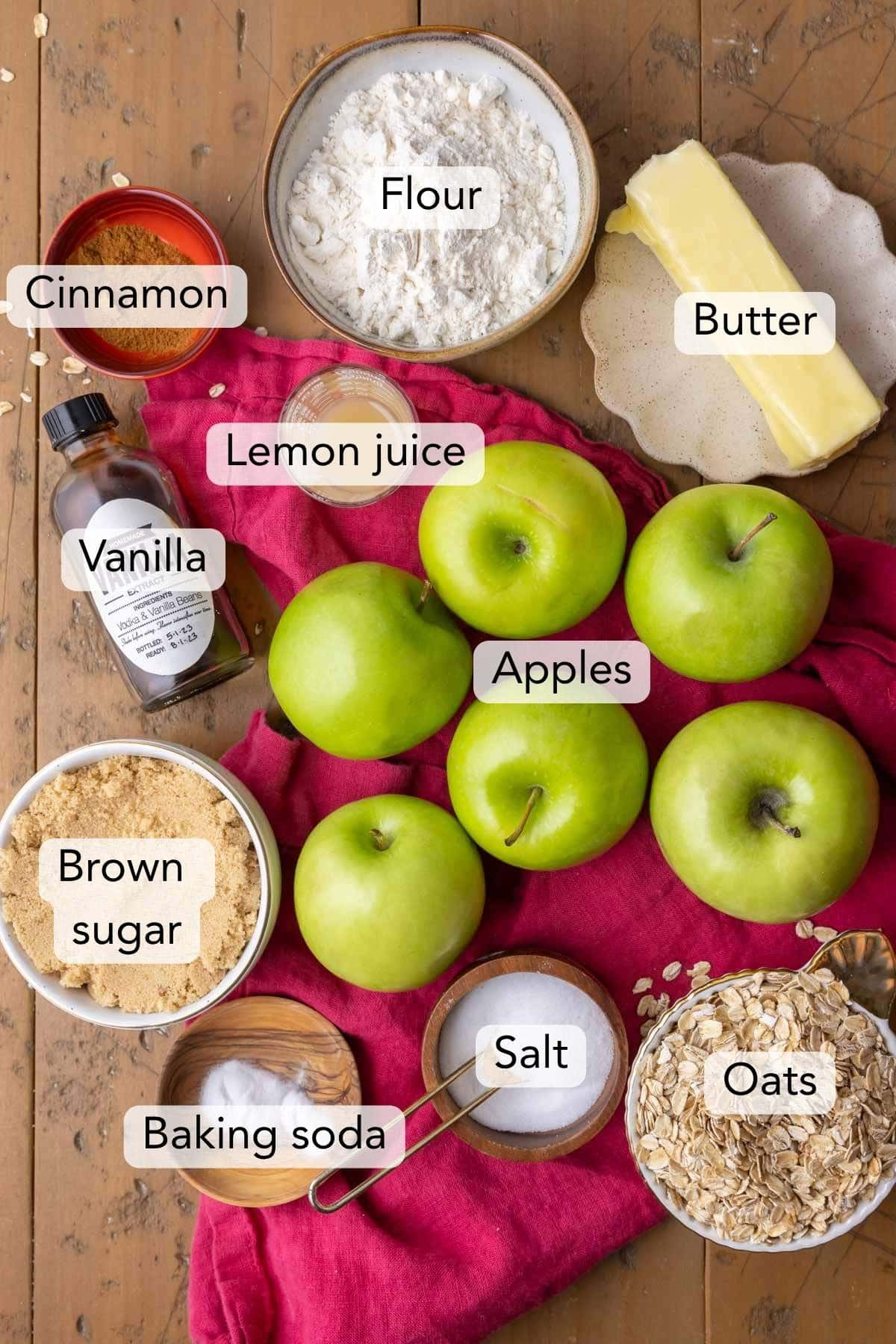 Overhead view of labeled ingredients for my apple crisp recipe, including apples, oats, brown sugar, and more.