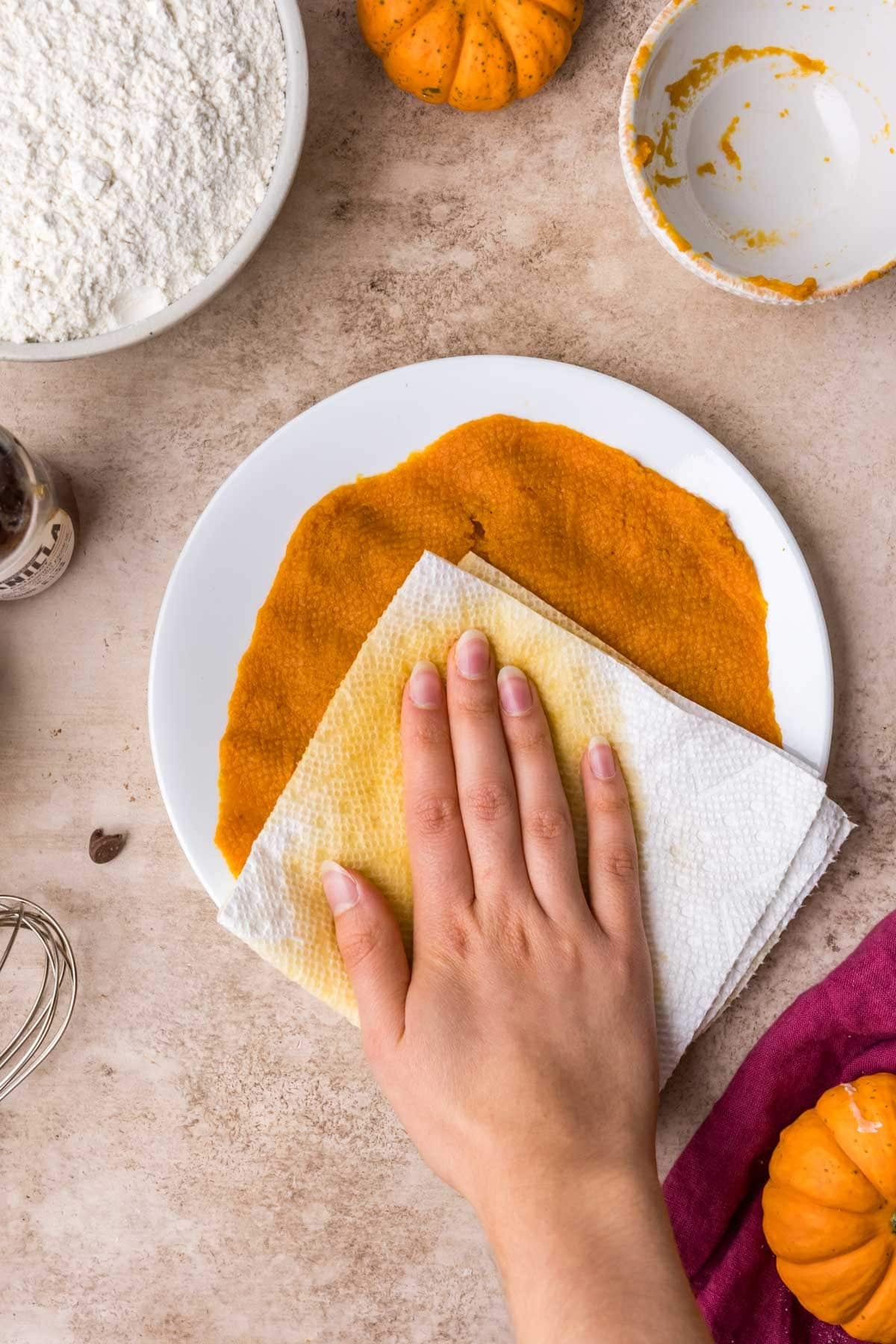 Using paper towels to blot pumpkin to remove the excess water.